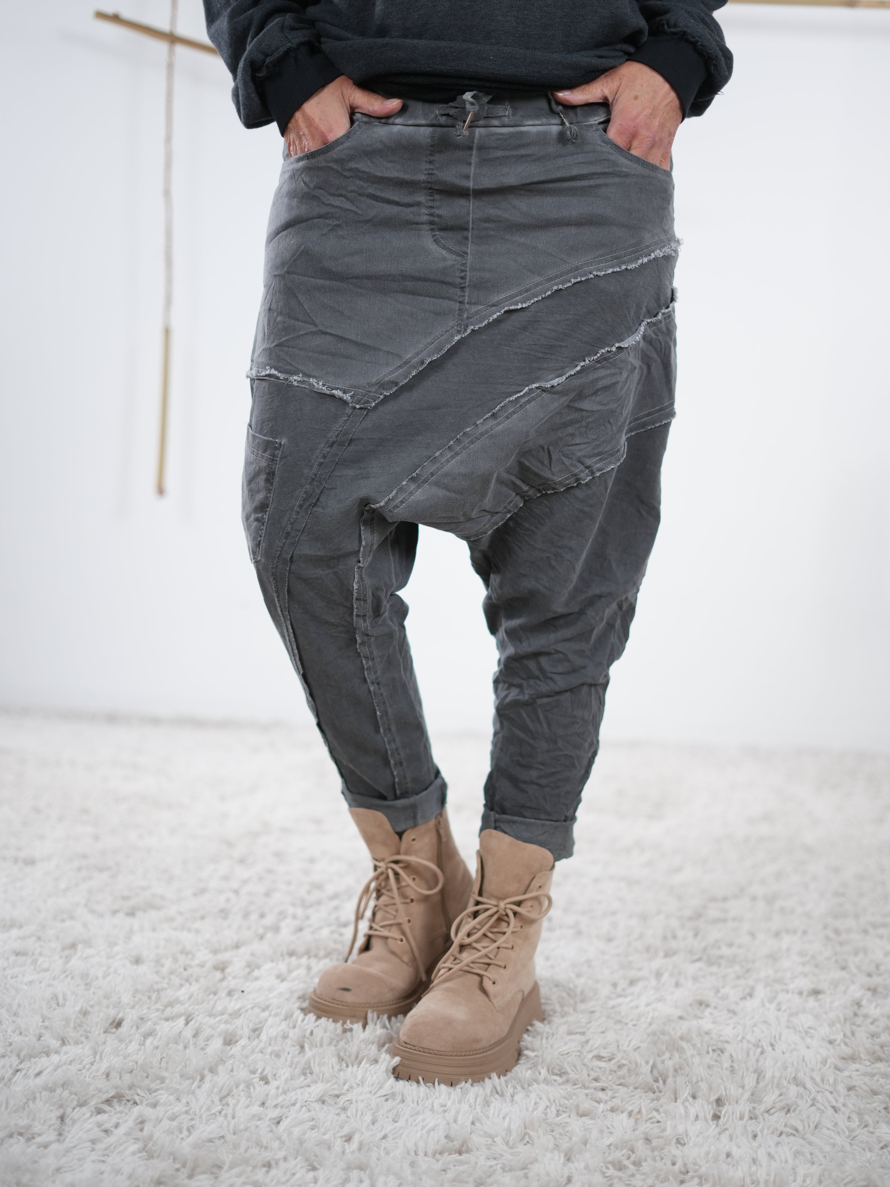 Baggyhose in Anthrazit mit auffälligen Außennaht-Details und tiefem Schritt, kombiniert mit beigefarbenen Boots.