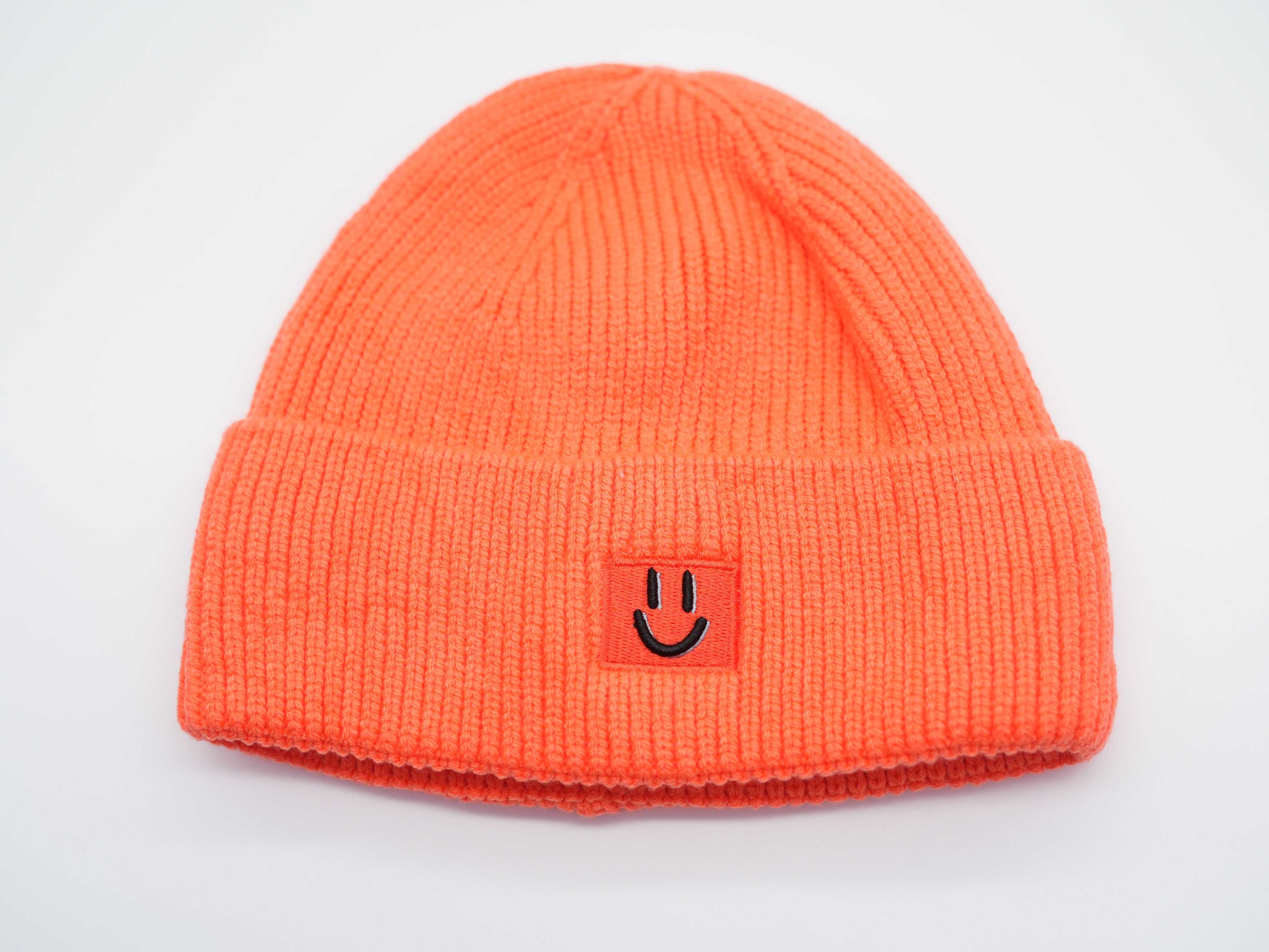 Orange Beanie Mütze für Damen aus dickem Rippstrick, vorne mit gesticktem Smiley-Patch.