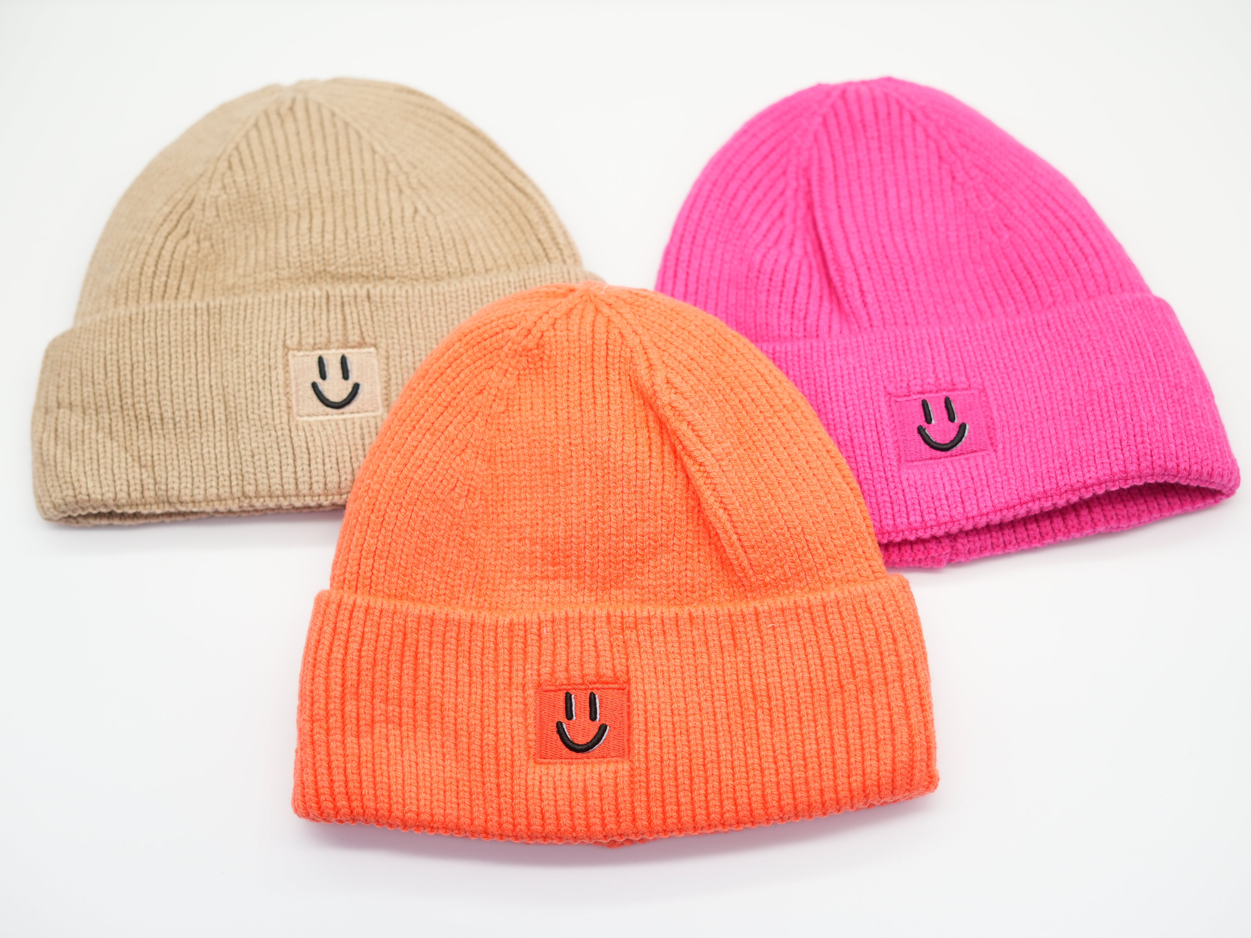 Set aus drei Damen Beanies in Beige, Orange und Pink, warme Strickmützen mit umgeschlagenem Saum und Smiley-Patch.