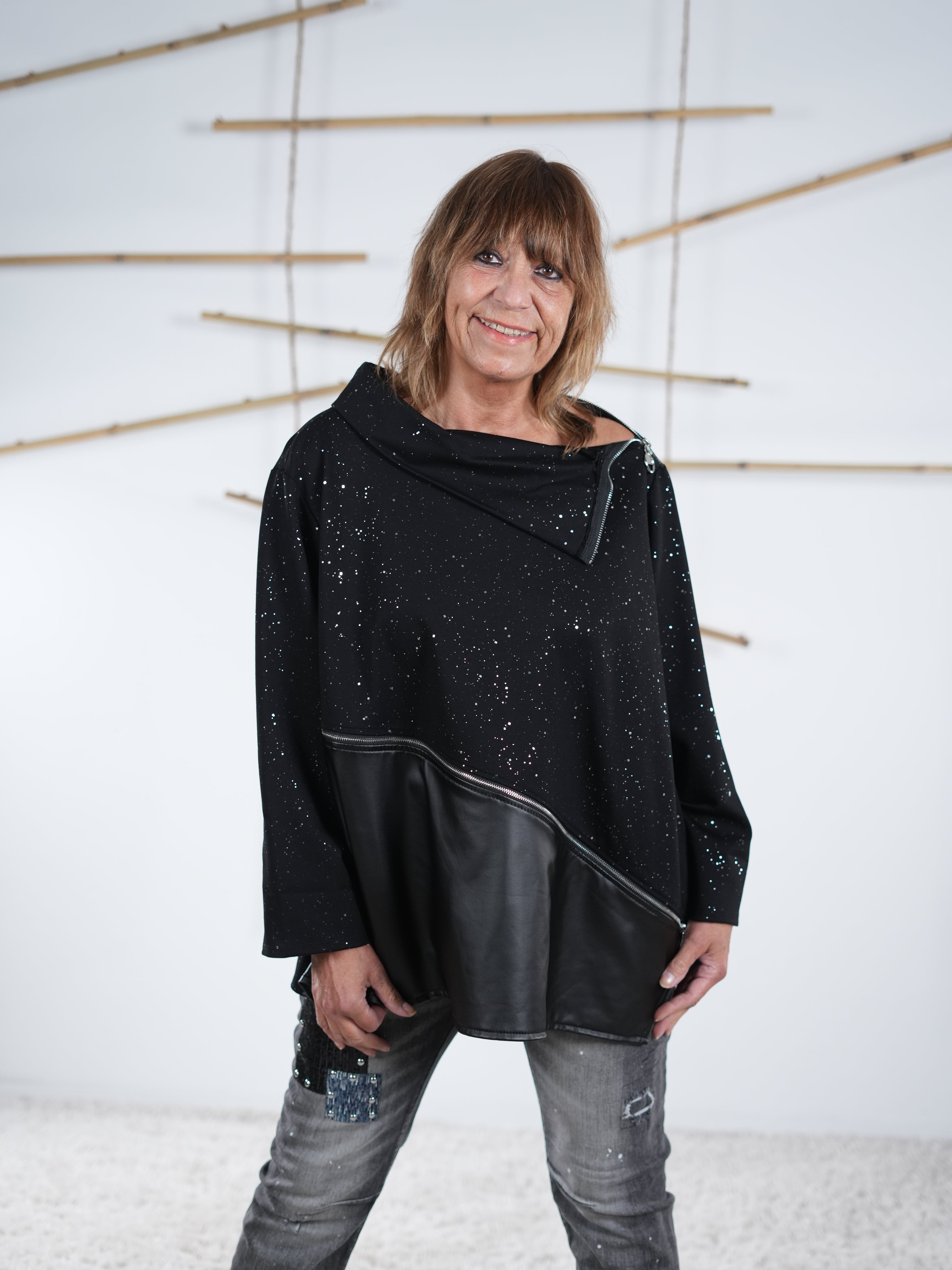 Schwarzer Glitzer-Pulli mit asymmetrischem Kunstleder-Abschluss und schrägem Zipper, vorne getragen