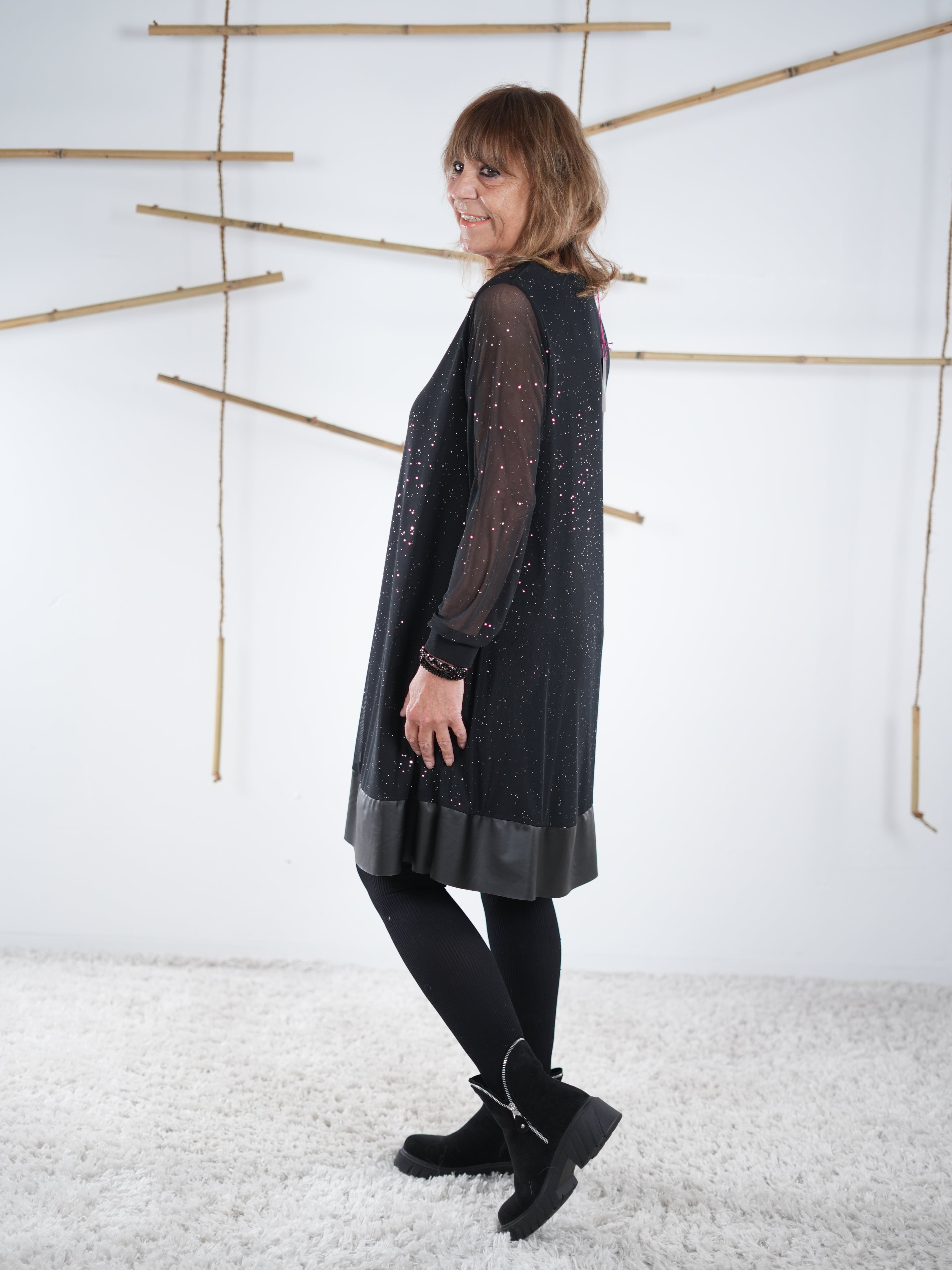 Detailansicht des schwarzen Glitzerkleids mit transparenten Ärmeln und leicht ausgestellter Form