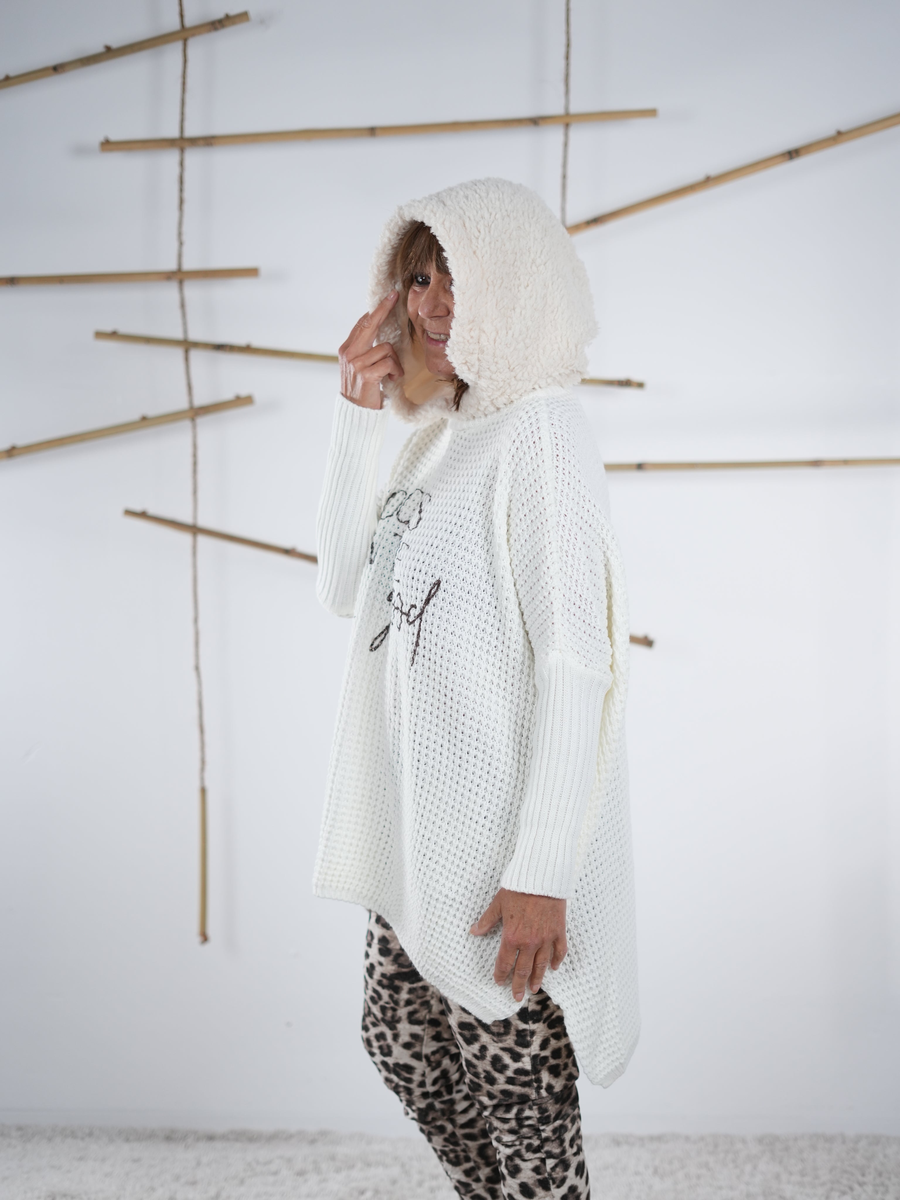 flauschiger Grobstrickpulli mit schwarzem Schriftzug in wollweiß. Marion präsentiert die seitliche Ansicht des Pullis.