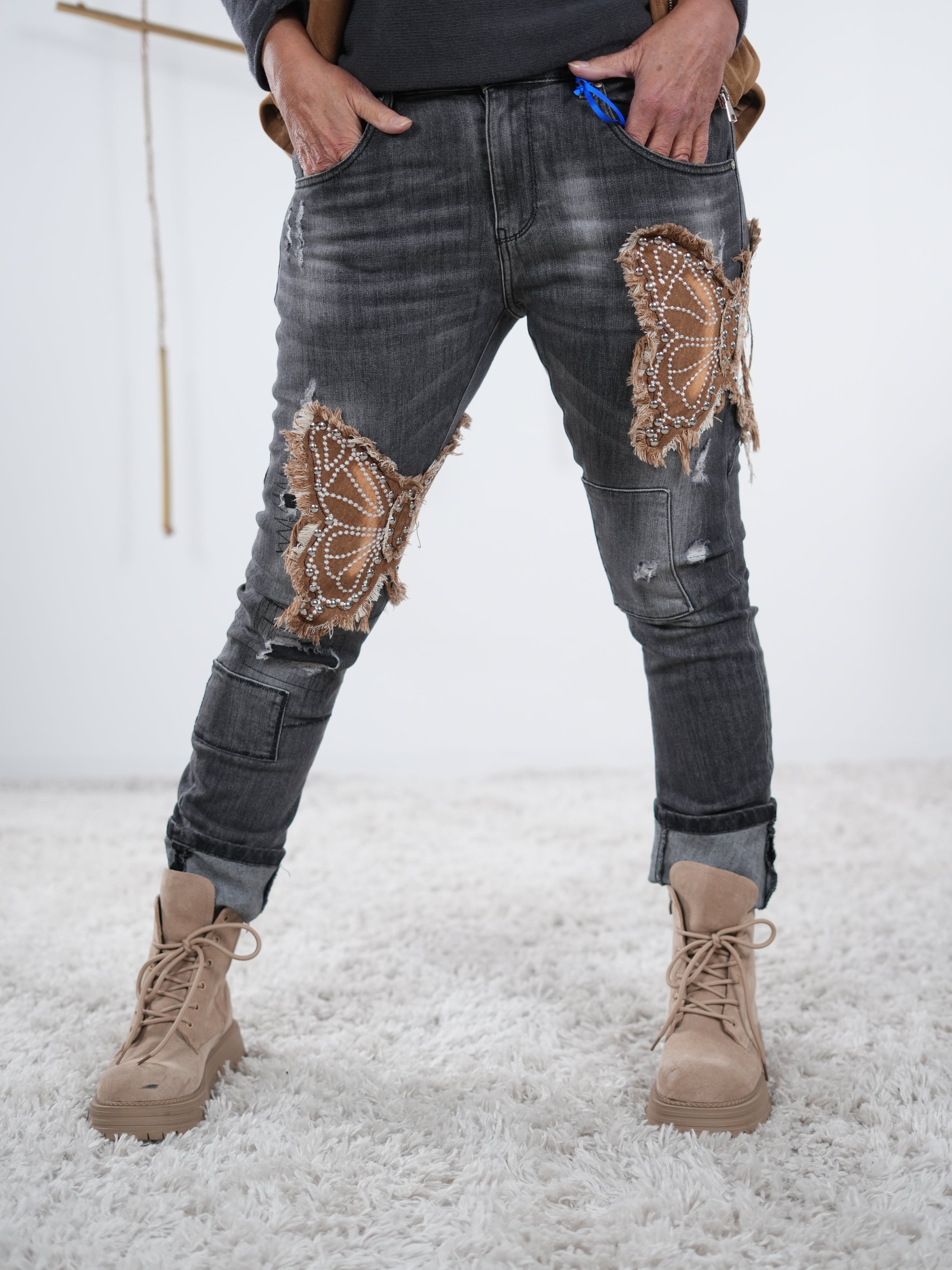 damen jeans in anthrazit mit präsentem schmetterlingspatch. lässige pose it großem abschluss, frontansicht