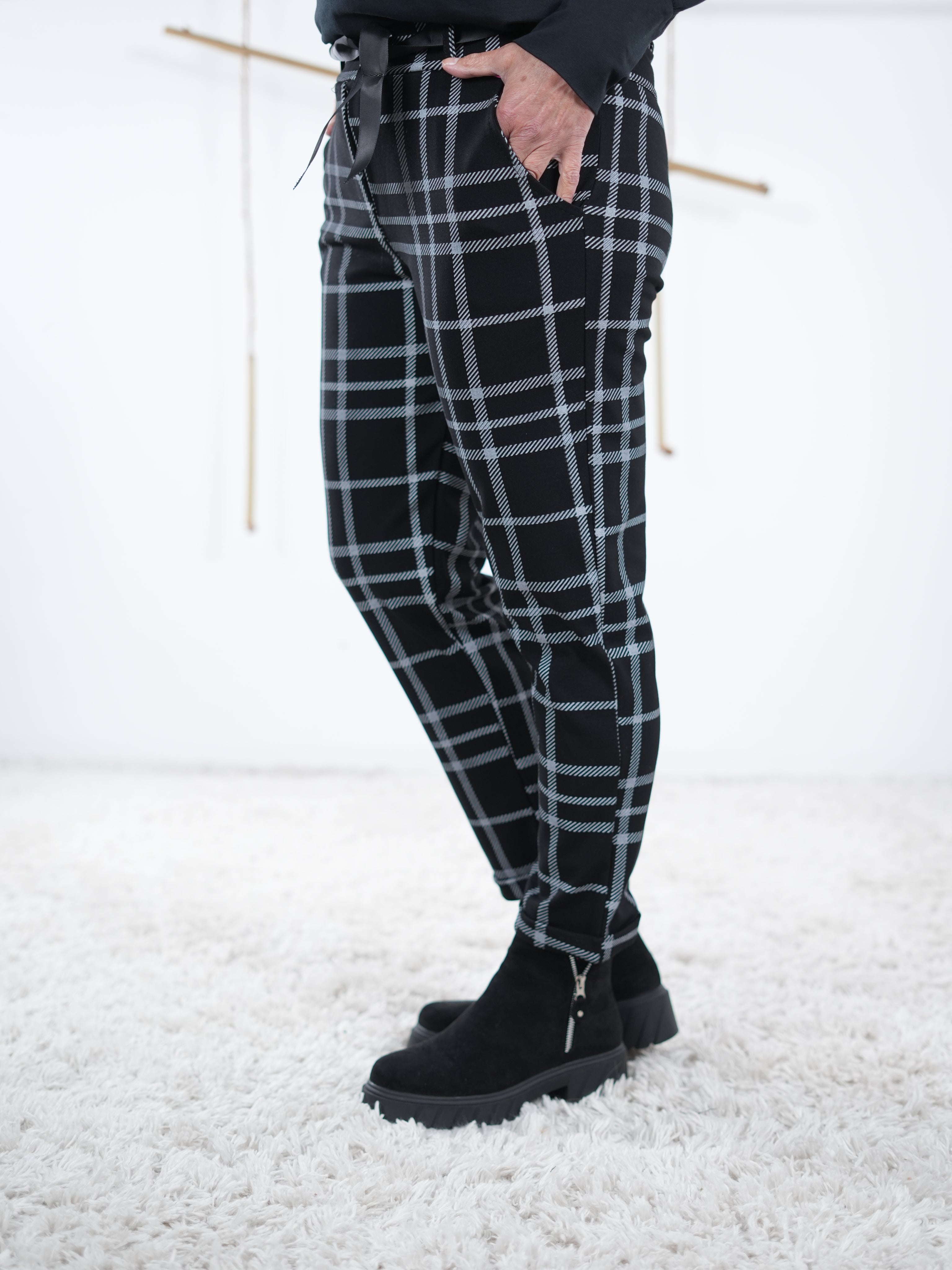 Seitliche Ansicht auf die karierte Jogpant. Das karierte Muster ist in schwarz weiß gehalten.