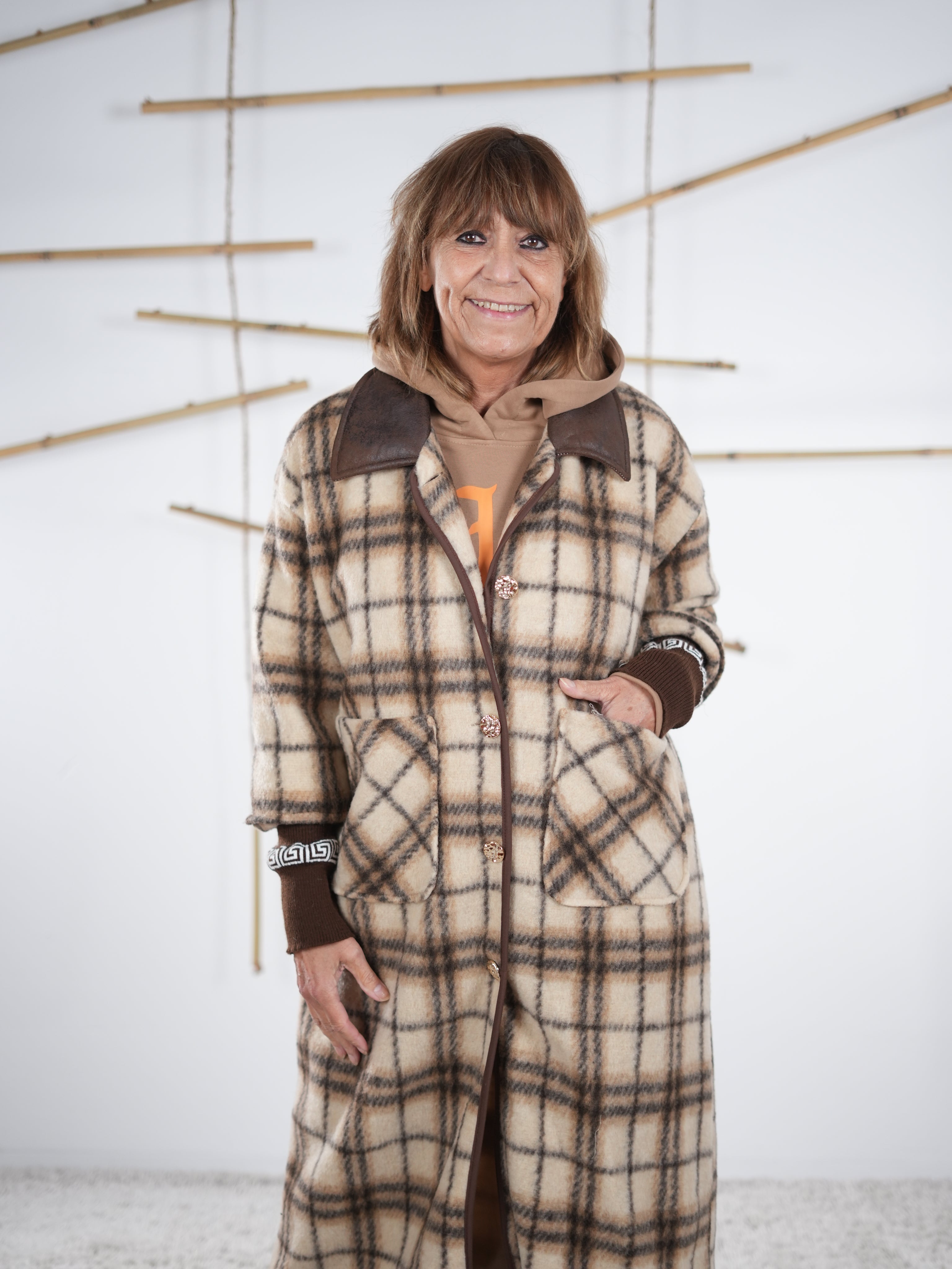 Frau trägt karierten Fleece-Mantel mit braunen Strickbündchen, Nahaufnahme der Vorderseite