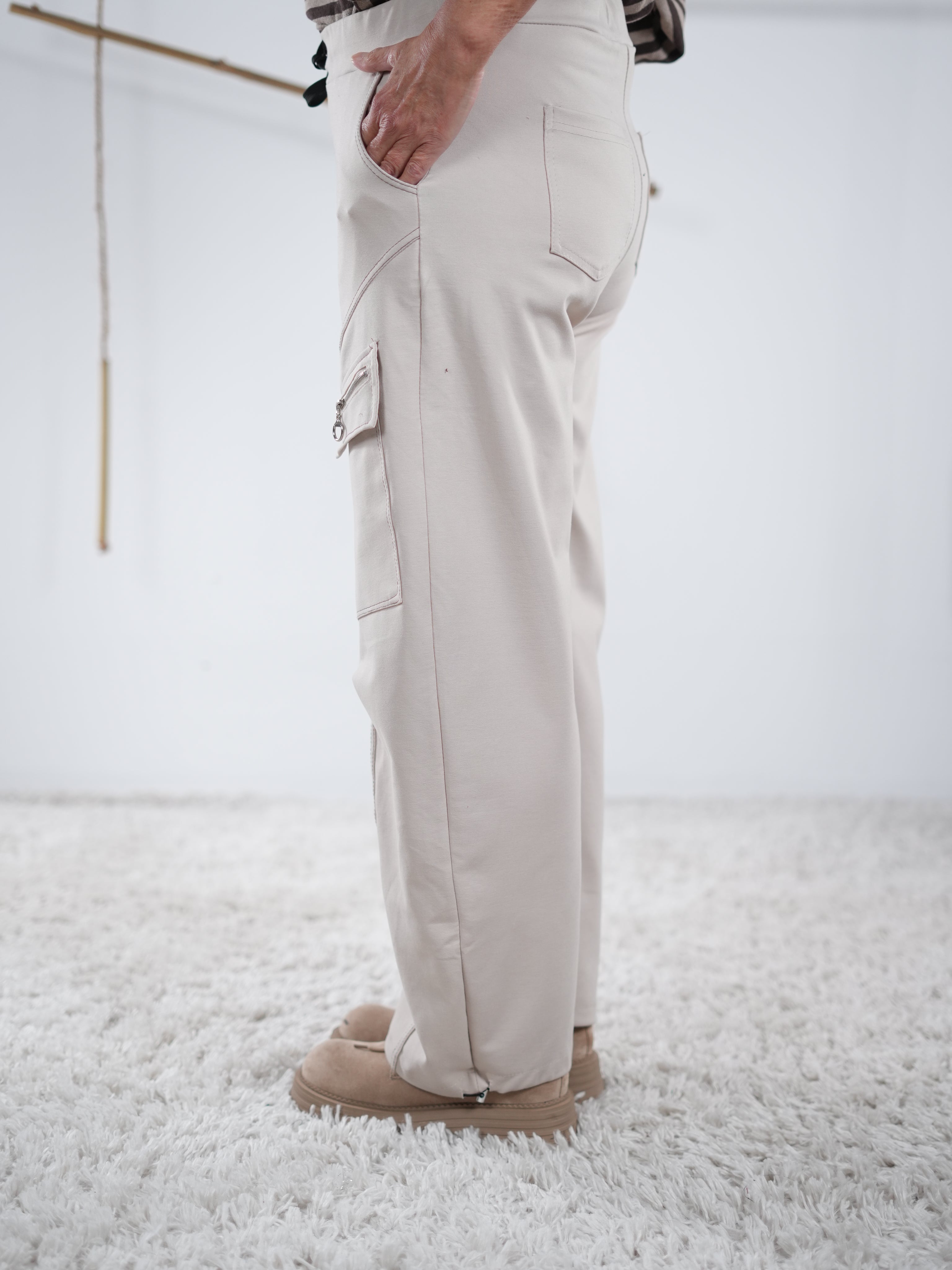 Seitenansicht einer beigen Cargo-Hose mit breitem Bein und Reißverschluss-Tasche am Bein