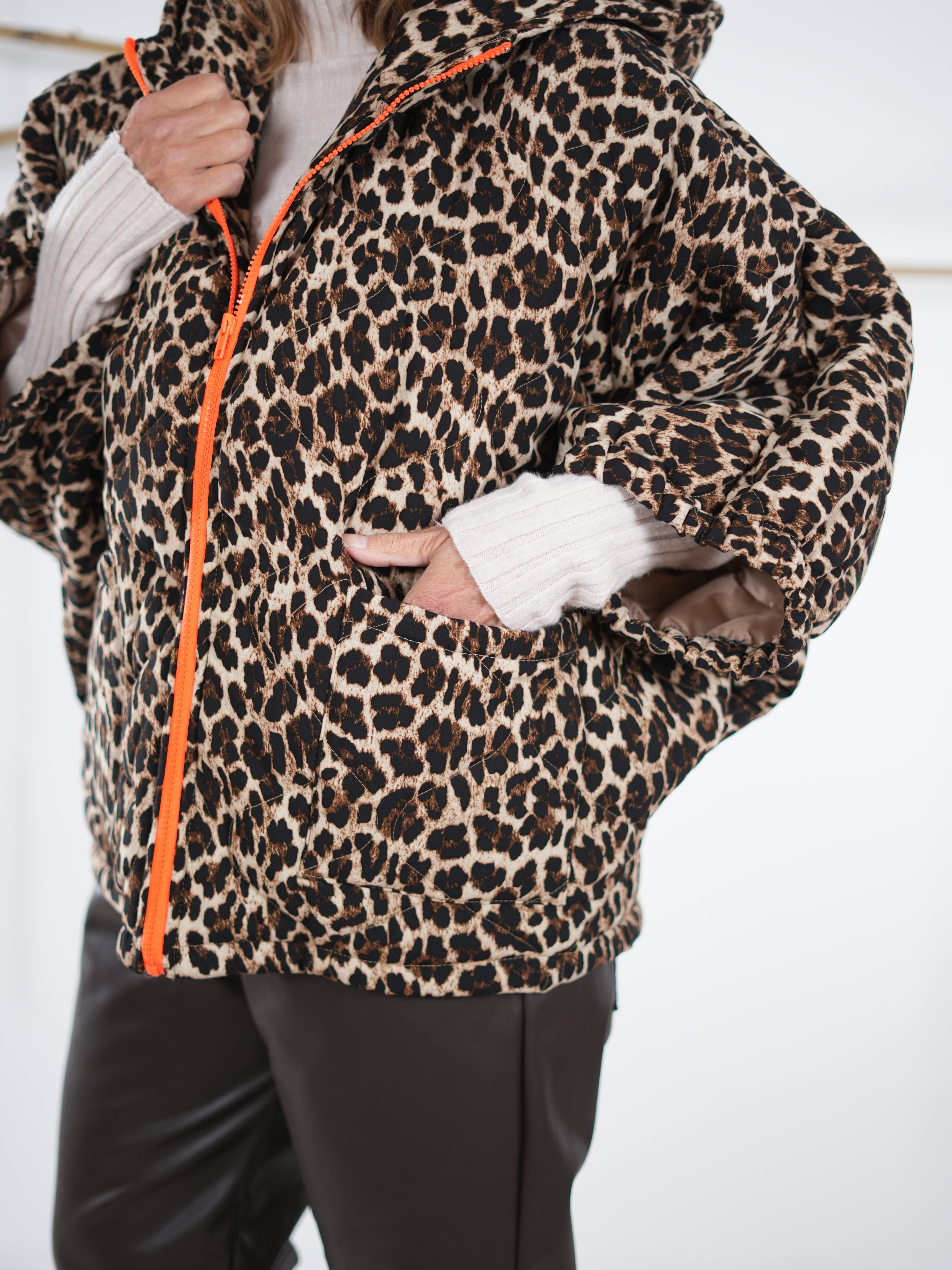 Modell trägt eine Leo-Oversize-Jacke mit orangem Reißverschluss, kombiniert mit dunkler Hose