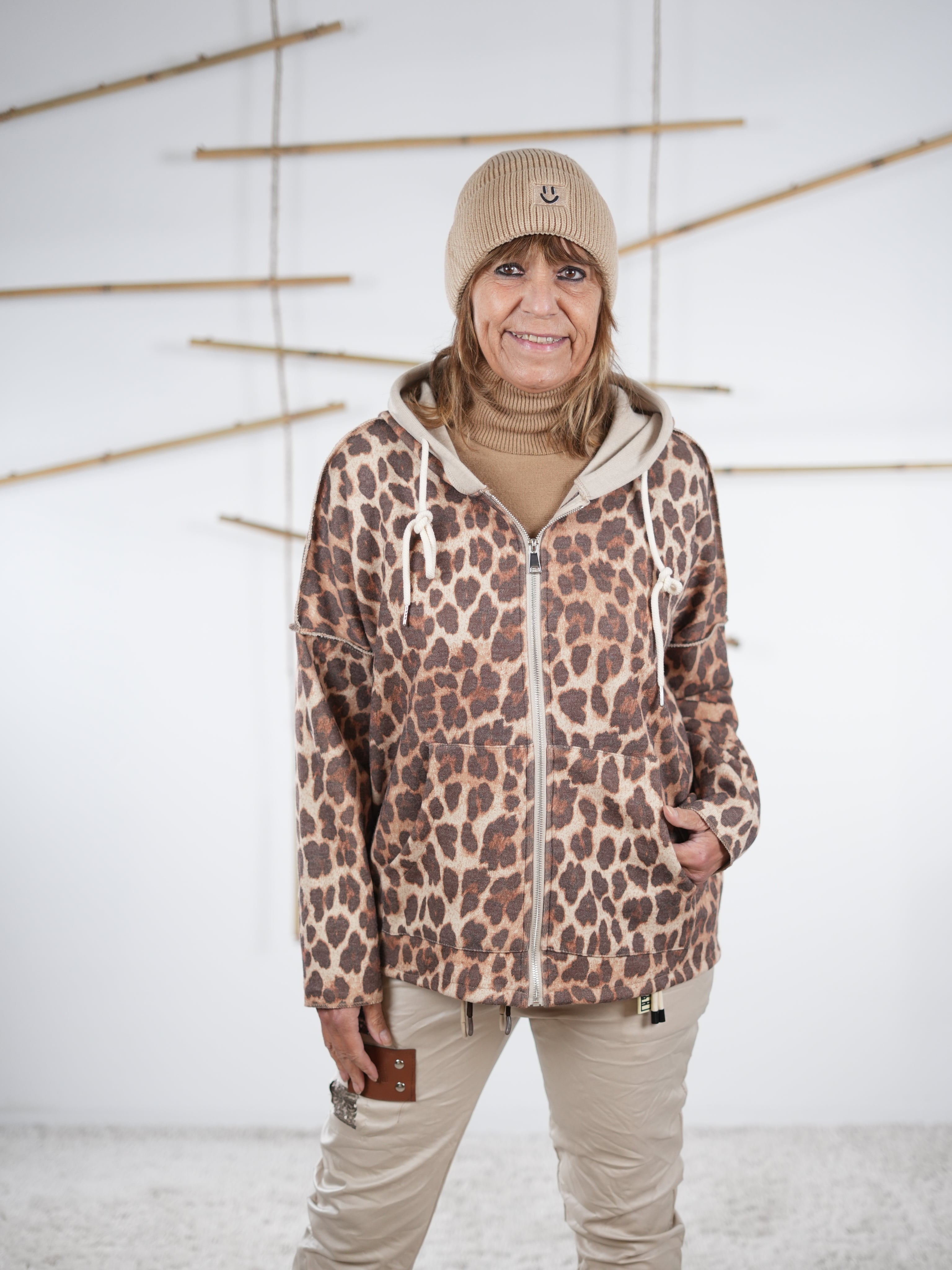 Camelfarbene Leo-Sweatjacke mit Kapuze und Fronttaschen im Stehen fotografiert.