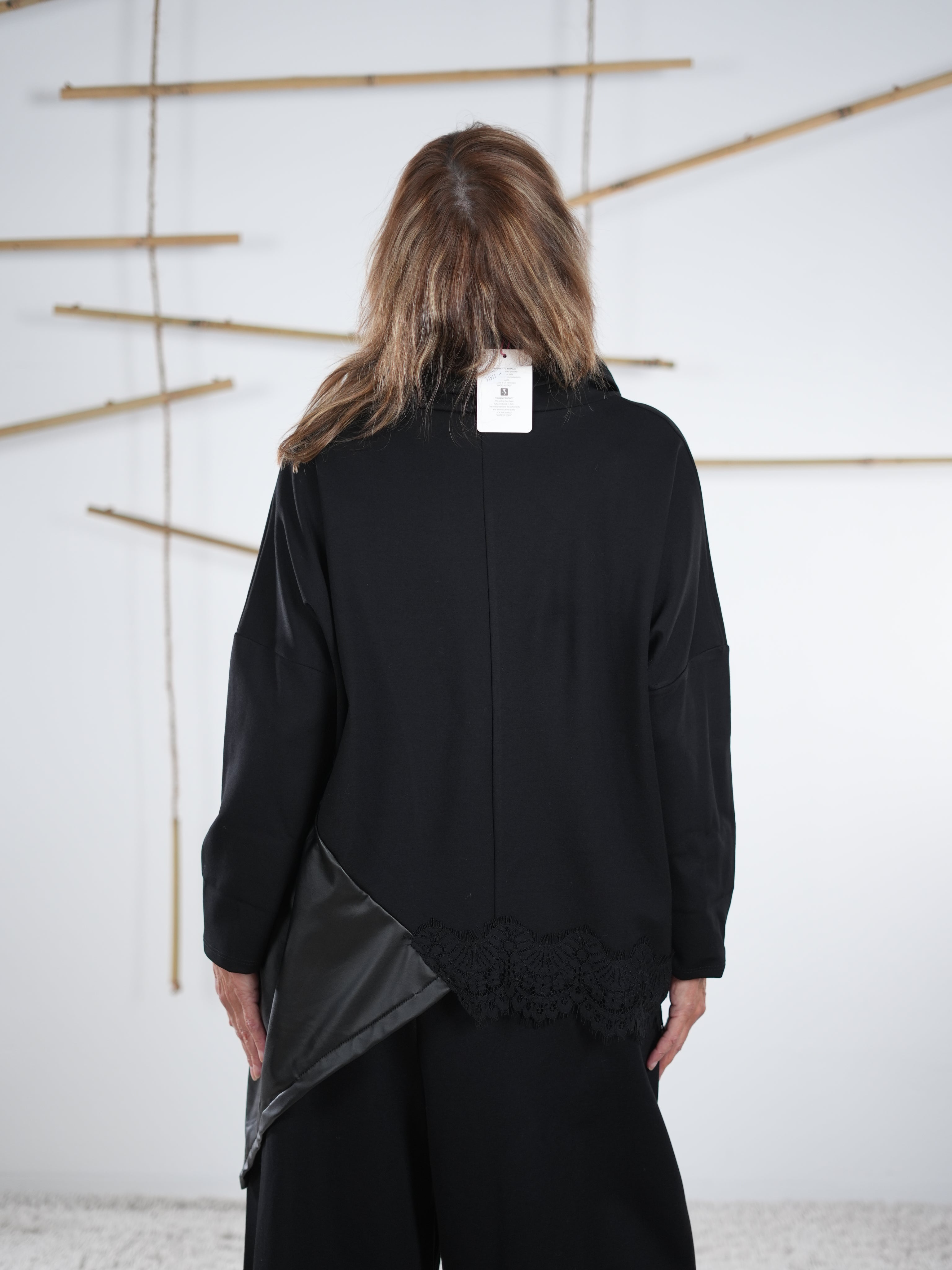 Rückansicht eines schwarzen Pullis mit Kunstleder-Einsatz und Spitzenkante, locker fallender Schnitt