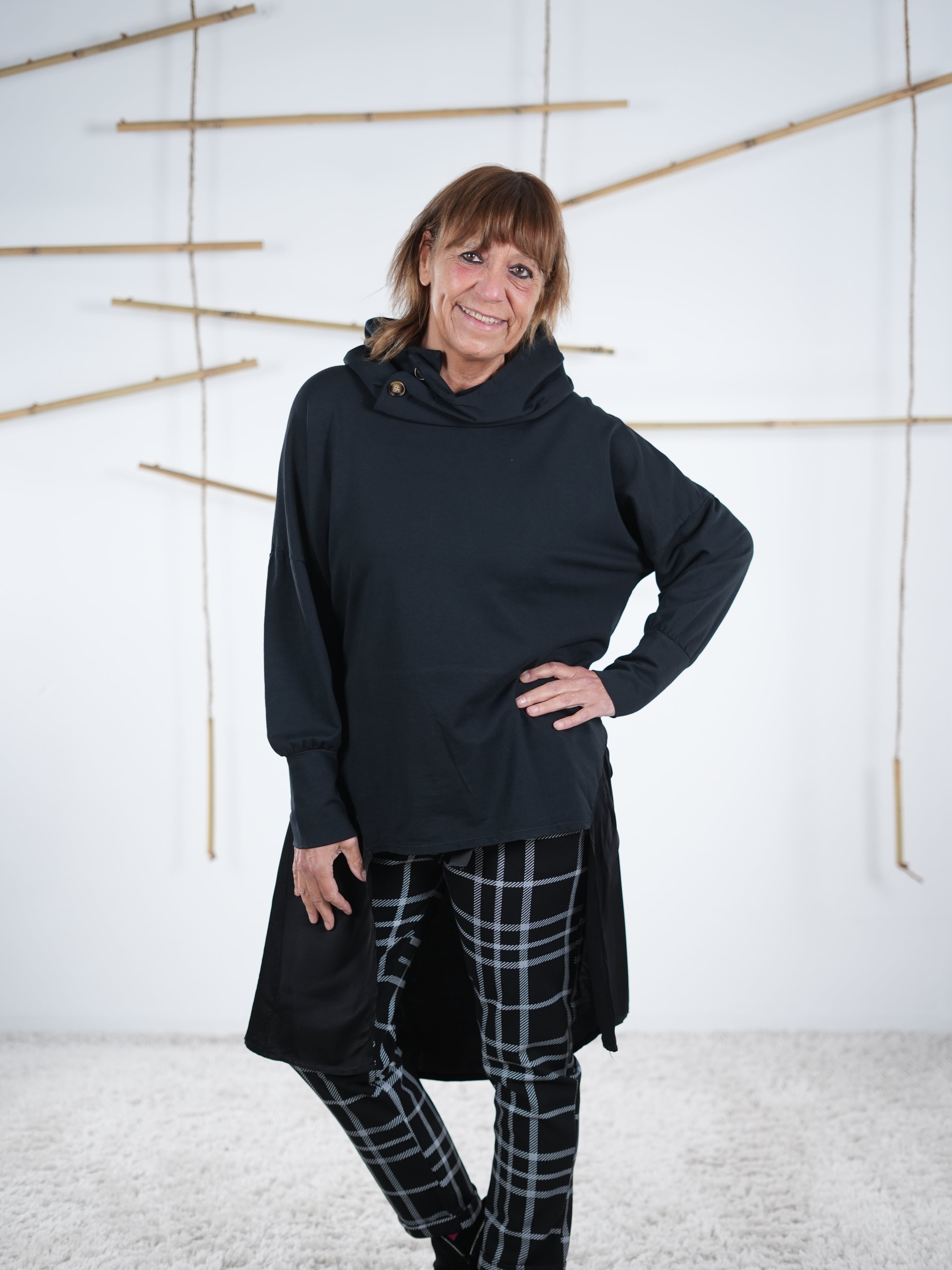 Schwarze modische Tunika mit seitlichem Satin-Stoff und Kapuze, feminine Vorderansicht.