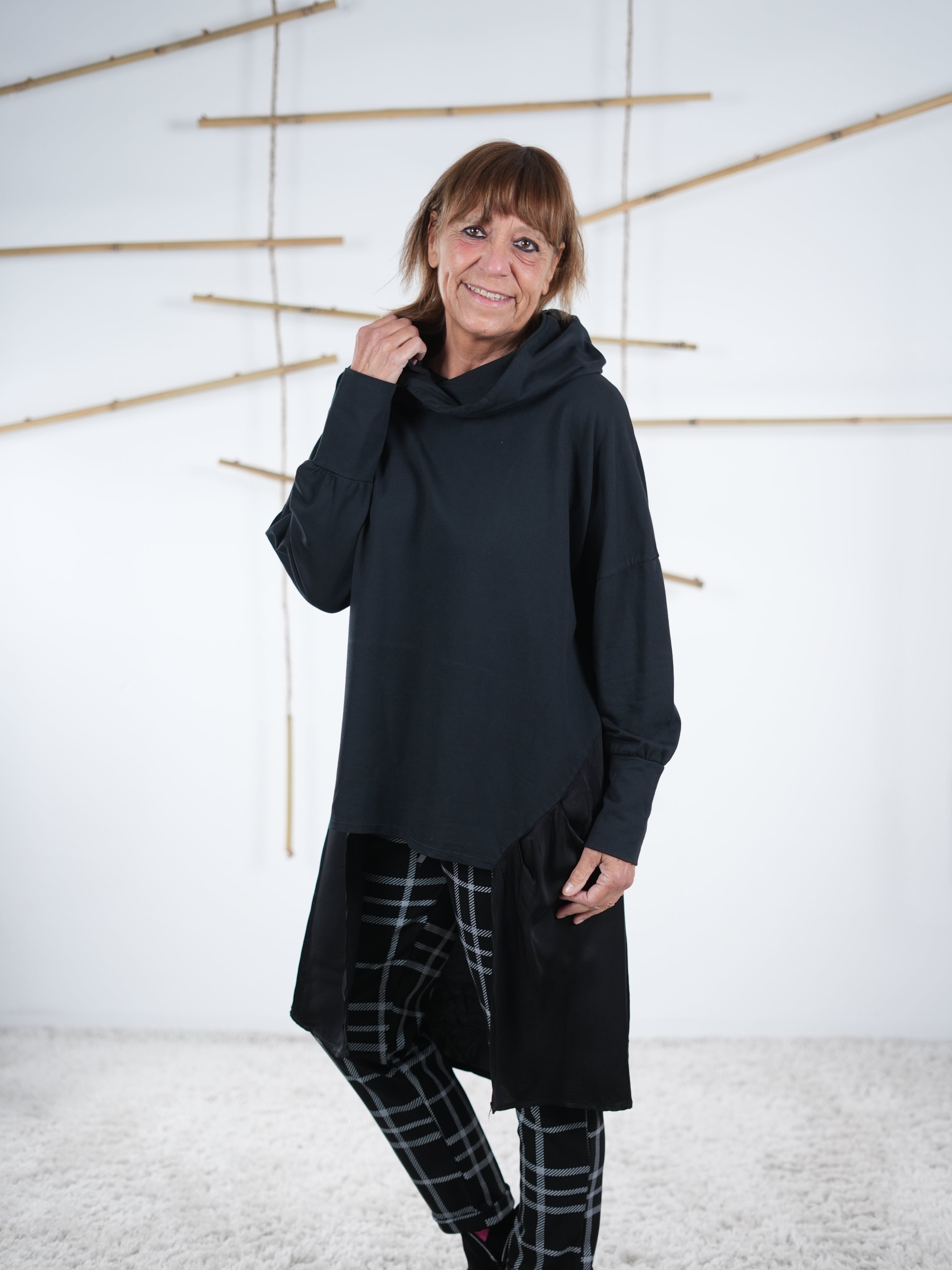 Moderne schwarze Damen-Tunika mit Satin-Einsatz, leicht gedrehte Ansicht, lässiger Schnitt.