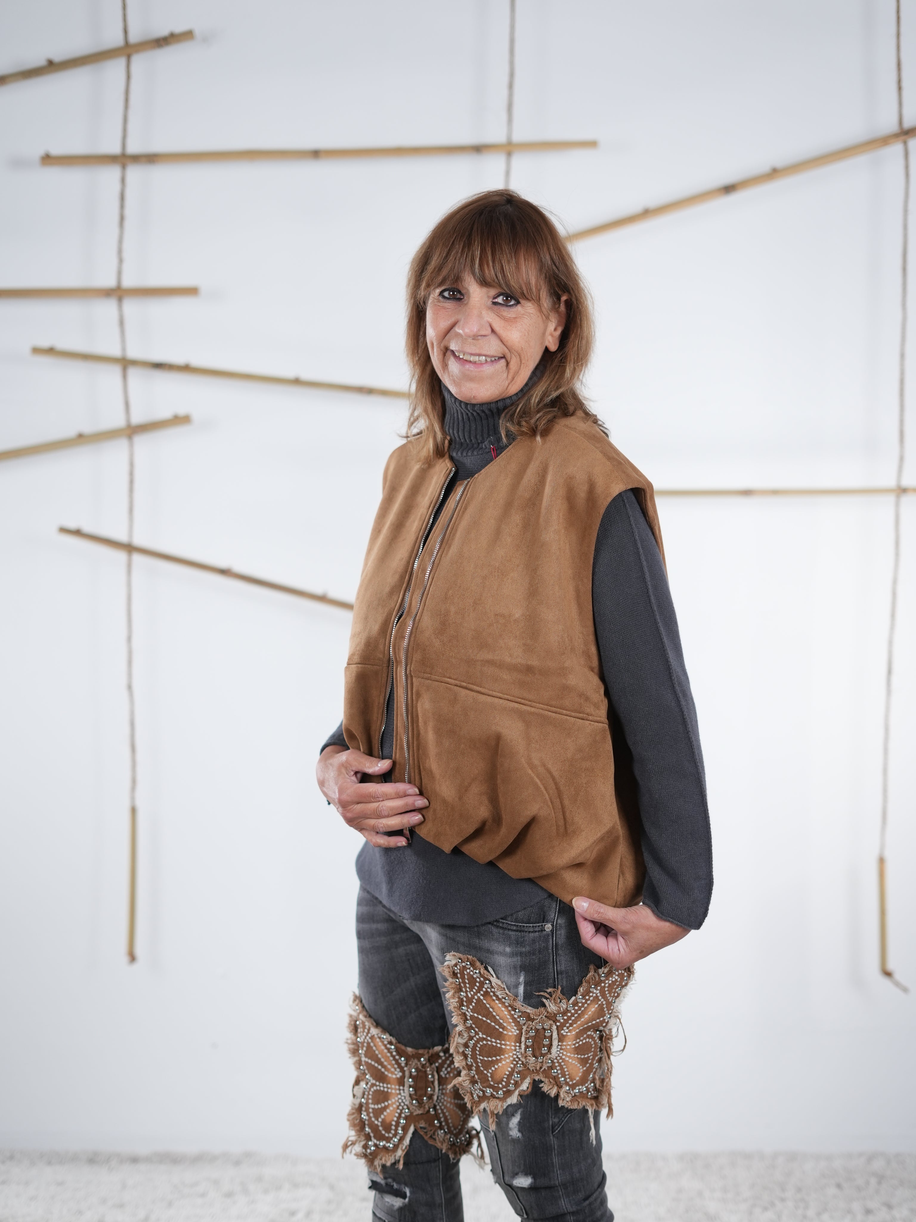 Seitliche Ansicht einer camelfarbenen Velours-Weste in Lederoptik mit Gummizug am Abschluss.