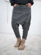 Baggyhose in Anthrazit mit auffälligen Außennaht-Details und tiefem Schritt, kombiniert mit beigefarbenen Boots.