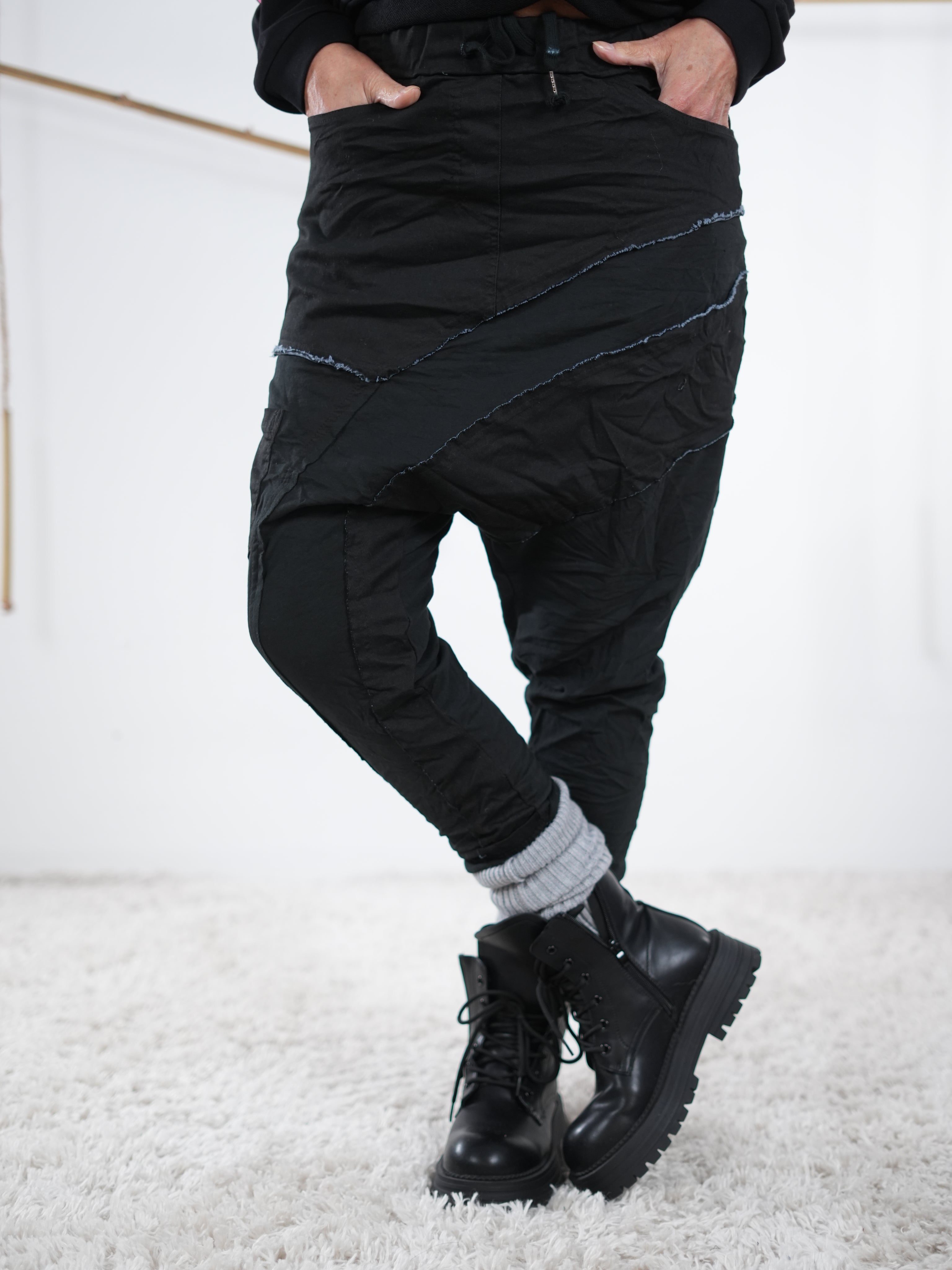 Baggyhose in Schwarz mit ausgeprägten Außennaht-Details und modernem, lässigem Look, kombiniert mit schwarzen Boots.