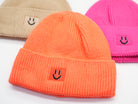 Damen Beanie Mützen in Beige, Orange und Pink aus Rippstrick, jeweils mit gesticktem Smiley-Patch auf der Front – Nahaufnahme