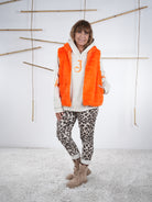 Knallig farbene Flausch-Weste offen getragen, locker fallend mit seitlichen Eingriffstaschen in orange.