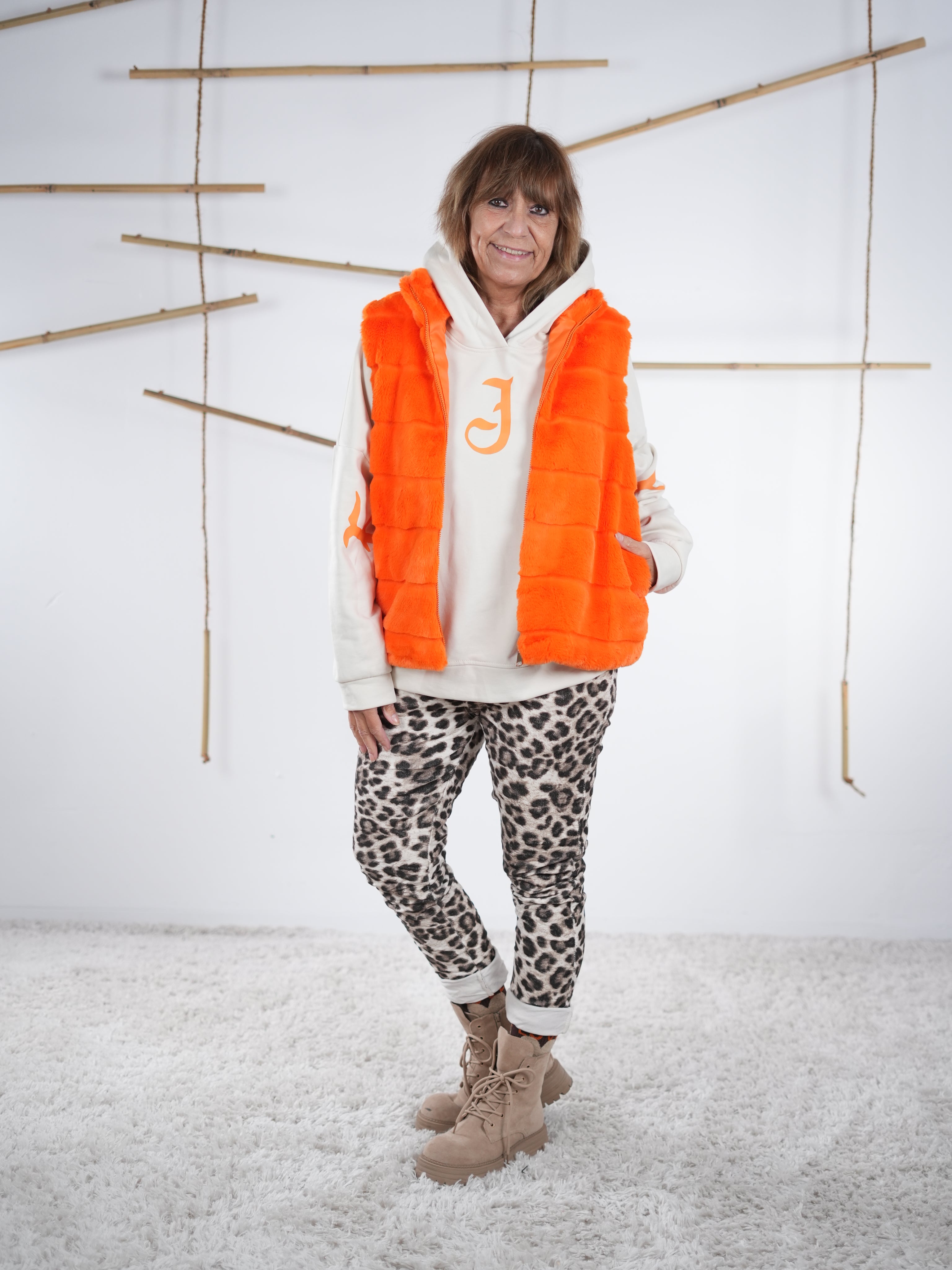 Knallig farbene Flausch-Weste offen getragen, locker fallend mit seitlichen Eingriffstaschen in orange.