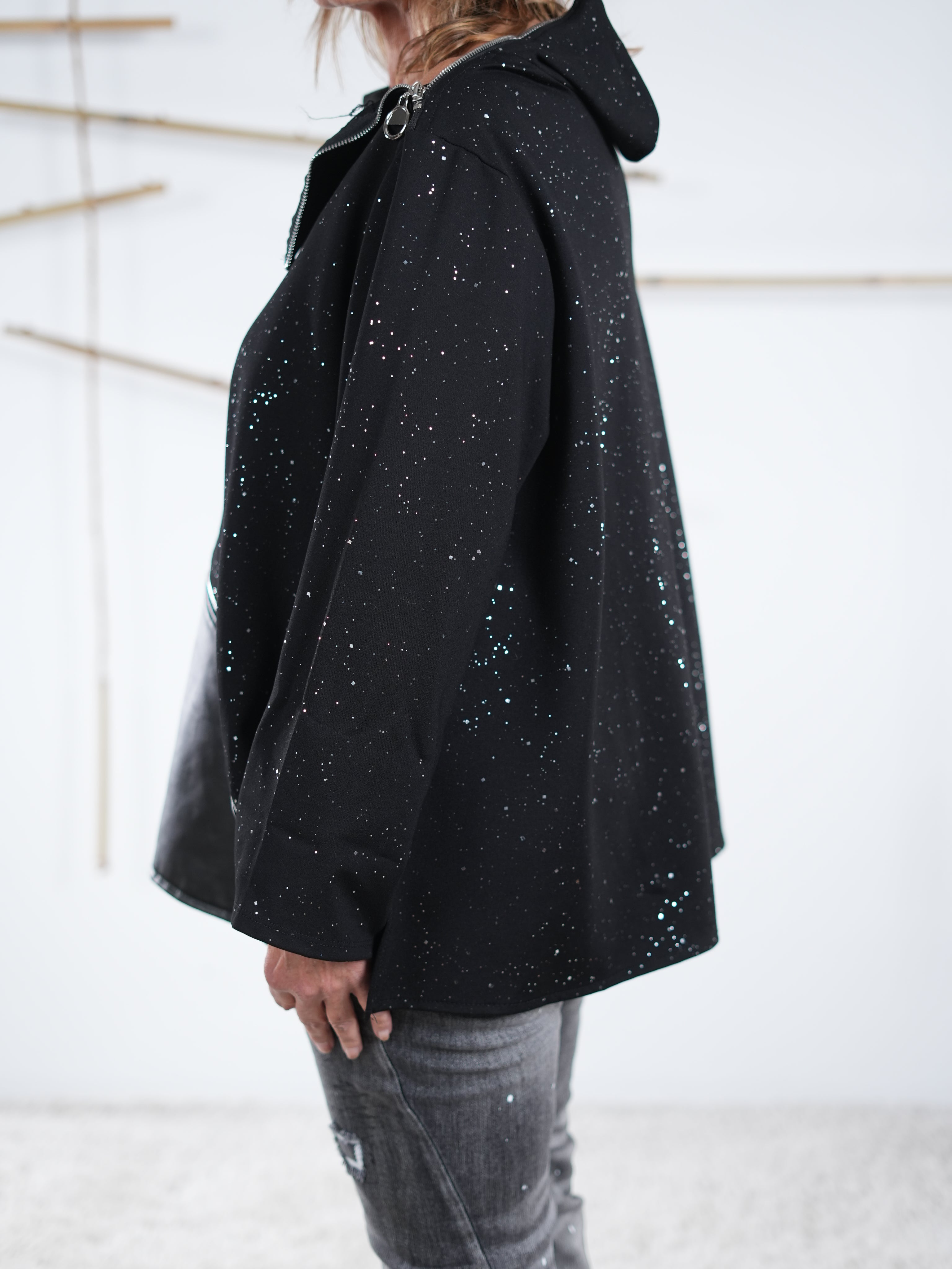 Seitenansicht eines schwarzen Glitzer-Pullis mit weit fallendem Schnitt und Kunstleder-Detail