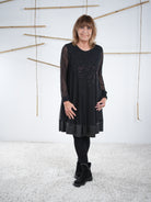 Schwarzes Glitzerkleid mit transparenten Ärmeln und Kunstleder-Saum, vorne getragen