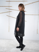 Detailansicht des schwarzen Glitzerkleids mit transparenten Ärmeln und leicht ausgestellter Form