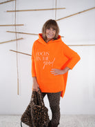 Orangefarbener Grobstrickpulli mit deutlich längerem Rückenteil und grobem Strick. Von Marion präsentiert.