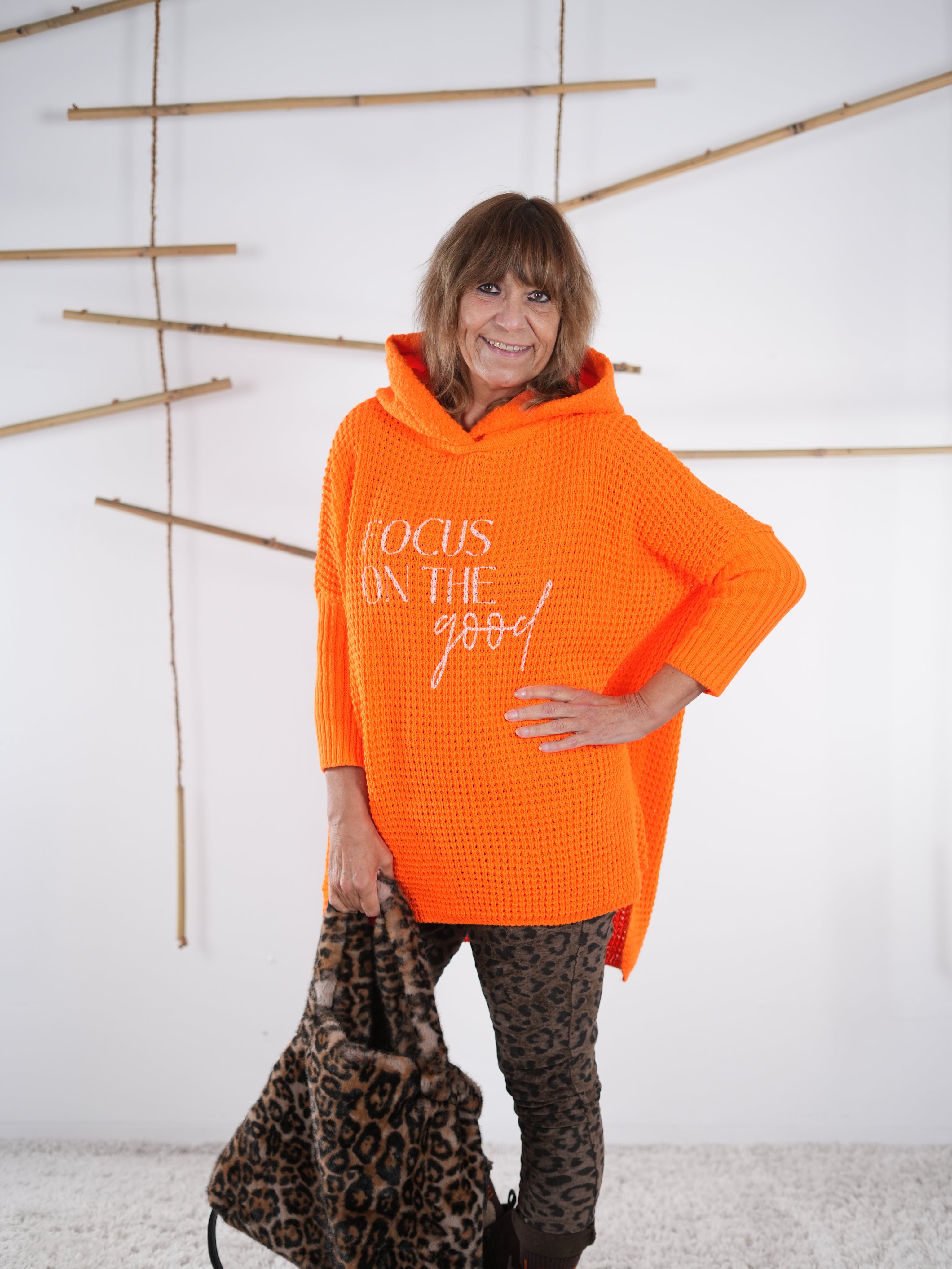 Orangefarbener Grobstrickpulli mit deutlich längerem Rückenteil und grobem Strick. Von Marion präsentiert.