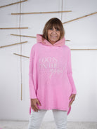 Rosafarbener Grobstrickpulli mit Kapuze, überschnittenen Ärmeln und lässigem Fit.