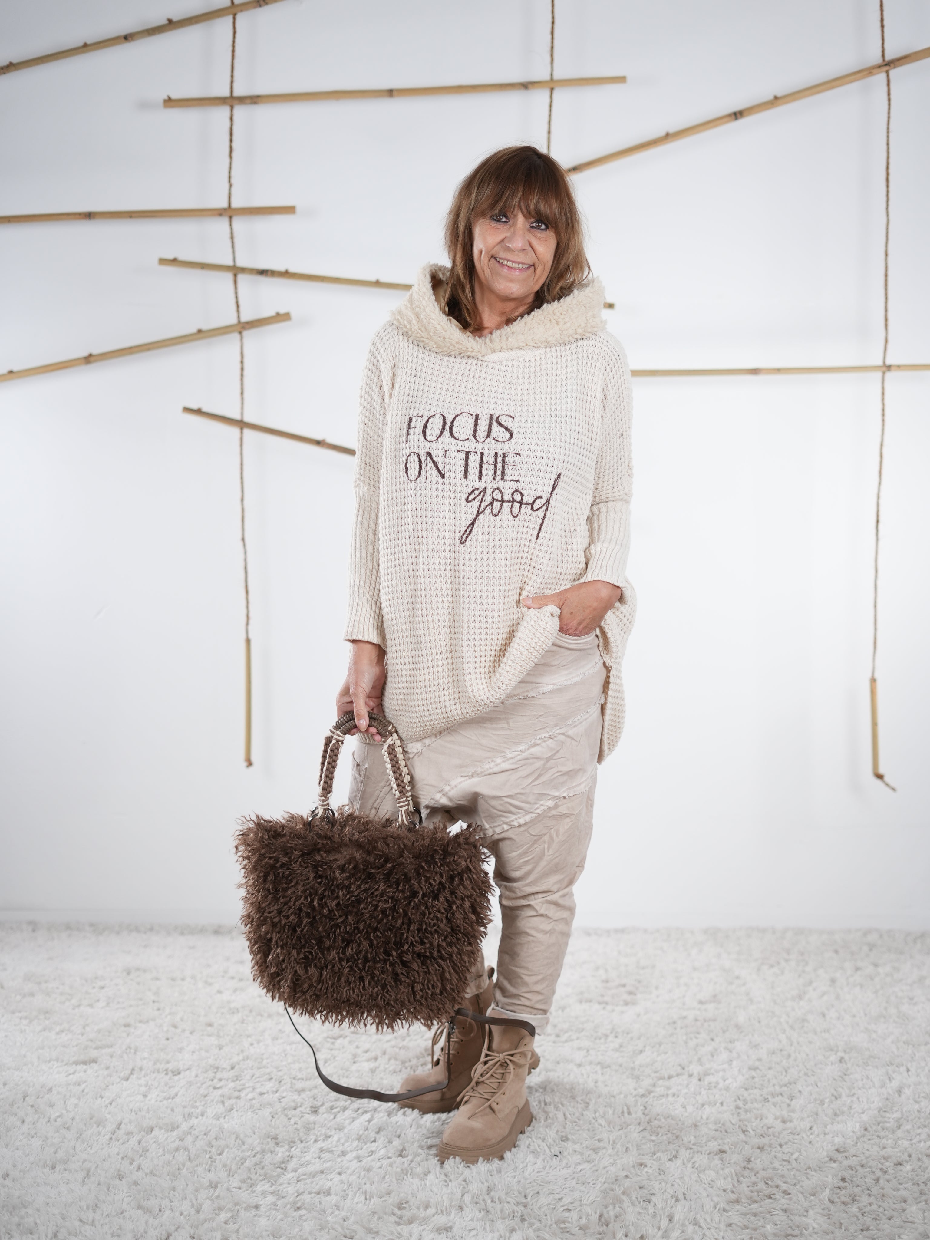 flauschiger Grobstrickpulli mit schwarzem Schriftzug in sand, kombiniert mit einer Baggy und süßen Accessoires.