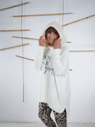 flauschiger Grobstrickpulli mit schwarzem Schriftzug in wollweiß. Detailaufnahme der flauschigen Kapuze.