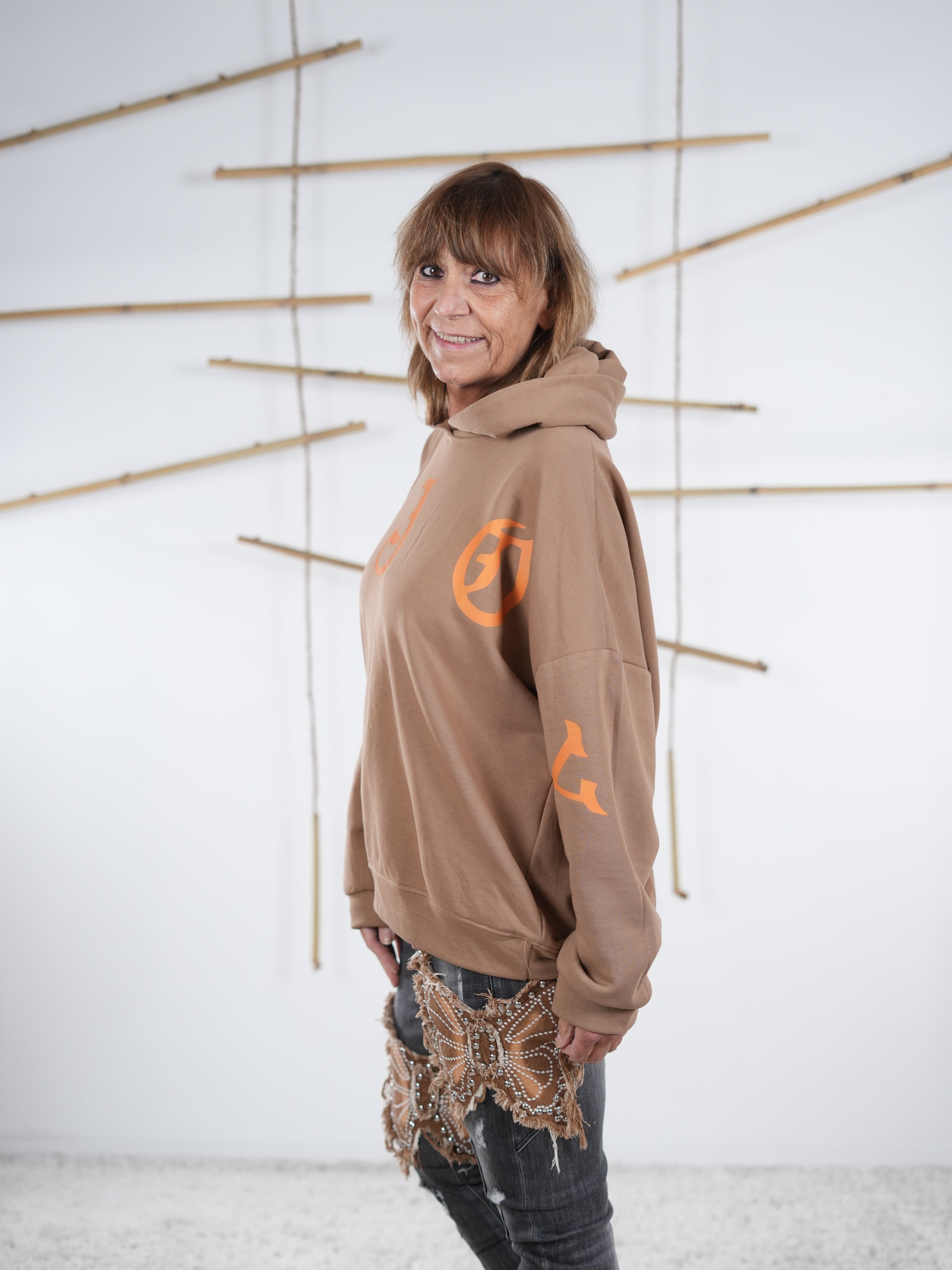 Damen-Hoodie in camel mit großem orangefarbenem Letter-Print vorne, seitliche Ansicht