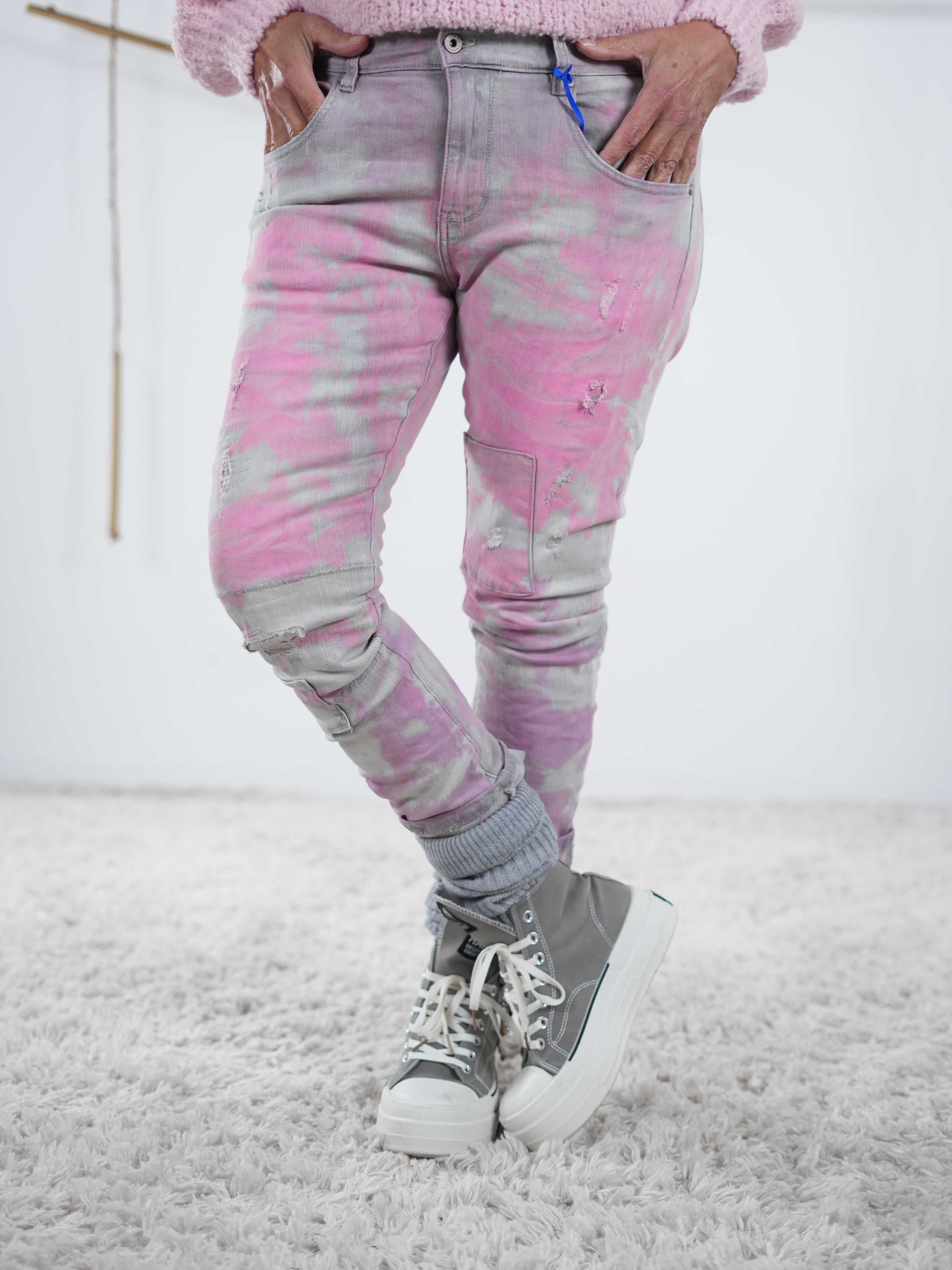 Frontansicht einer grauen Jeans Hose mit pinken Details. Fokus liegt auch auf den seitlichen Eingriffstaschen.