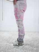 Seitliche Ansicht auf deine eng anliegende, graue Jeans mit pinken Details. Die Jeans hat einen breiten Abschluss.