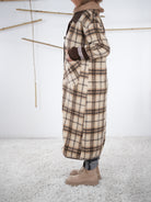 Seitenansicht eines langen karierten Fleece-Mantels in Beige-Braun, getragen von einer Frau