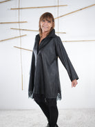 Seitliche Ansicht einer schwarzen Kunstleder-Tunika mit Spitzendetails.