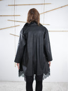 Rückansicht der schwarzen Kunstleder-Tunika mit dekorativer Spitze.