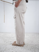 Seitenansicht einer beigen Cargo-Hose mit breitem Bein und Reißverschluss-Tasche am Bein