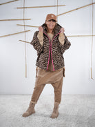 Modell in Leo-Jacke mit pinkem Reißverschluss und Oversize-Fit, kombiniert mit beigefarbener Hose