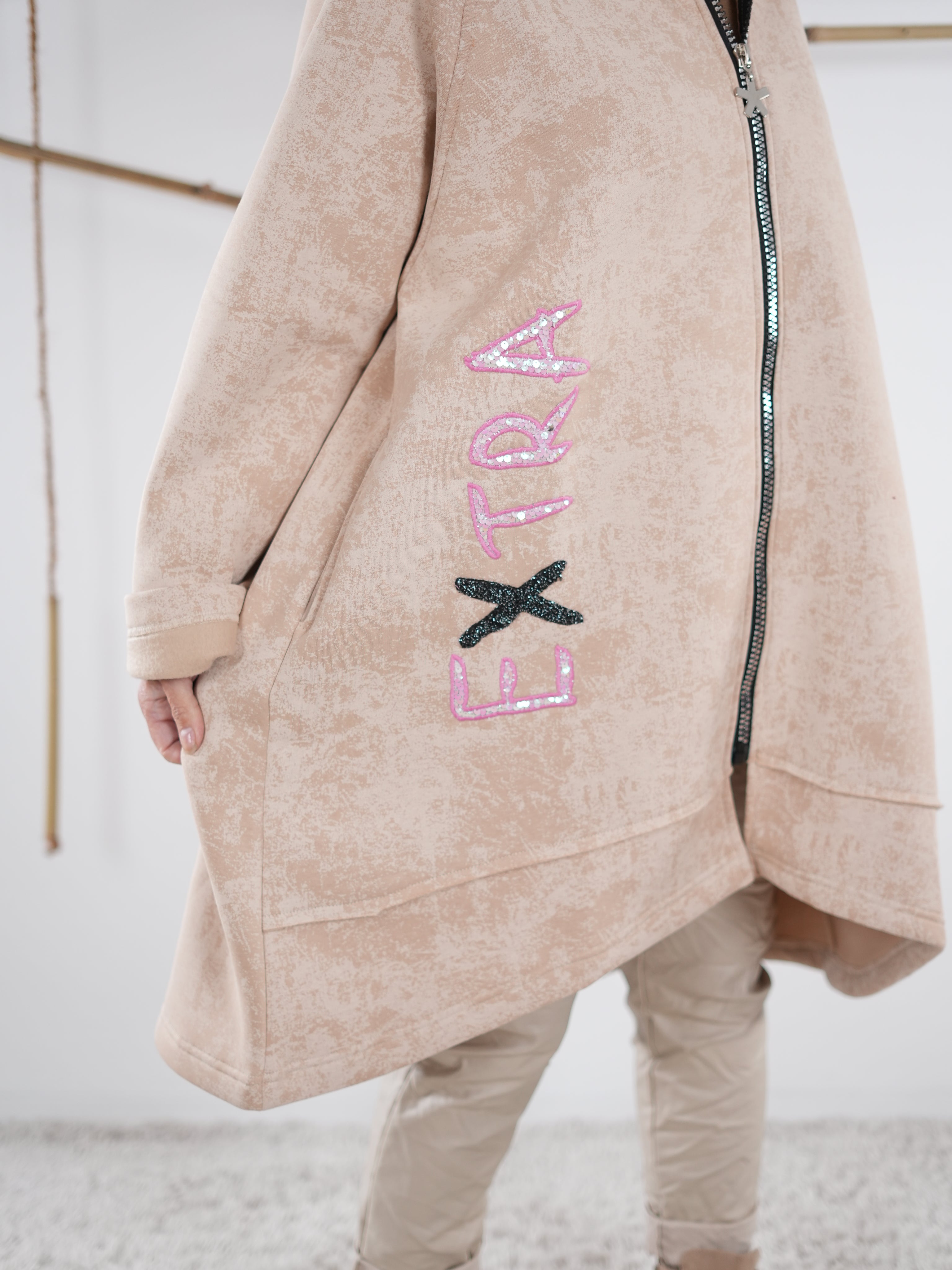 Detailaufnahme Schriftzug EXTRA auf dem beige Mantel