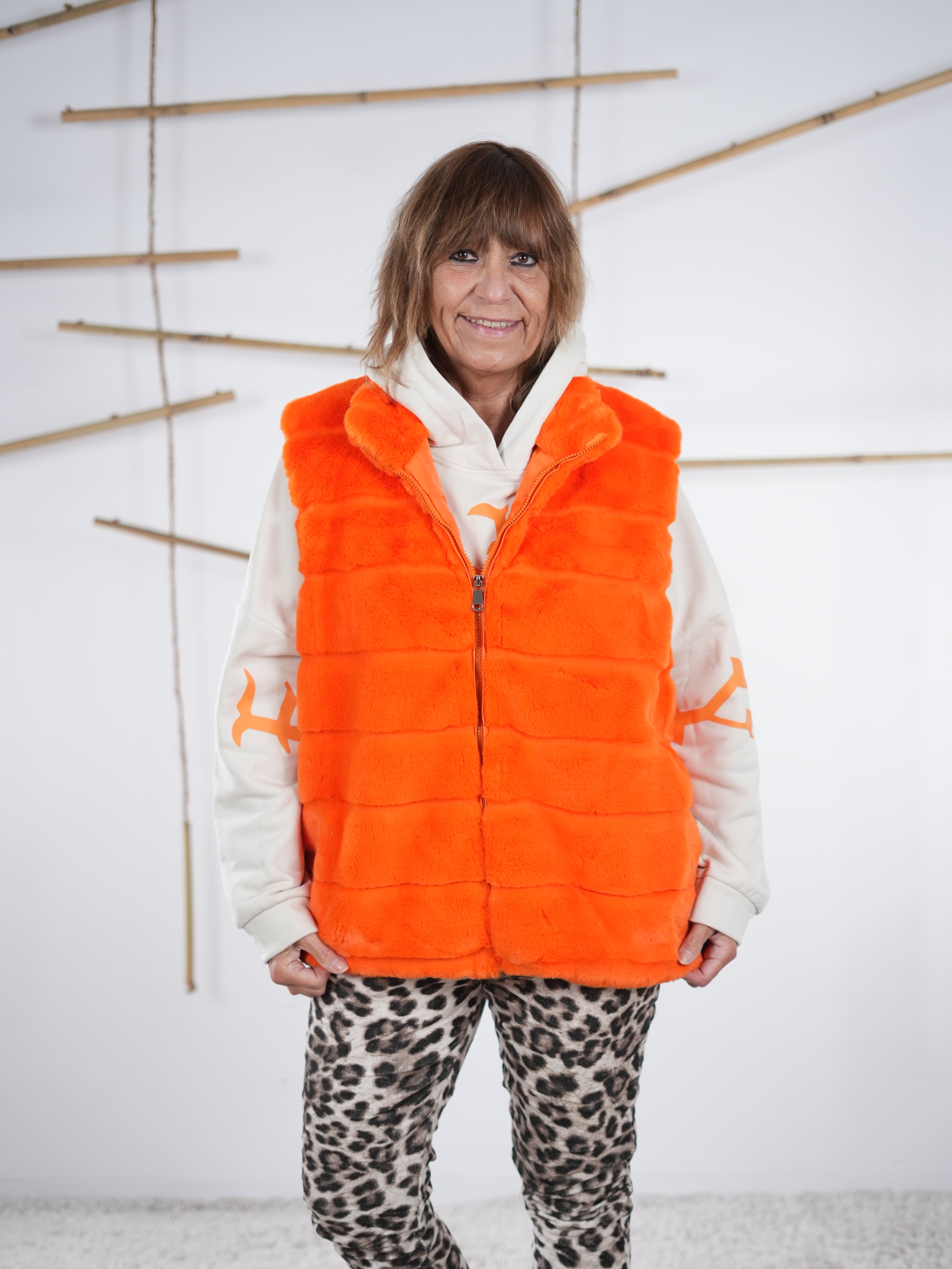 Orangefarbene Flausch-Weste mit Zipper in der Frontansicht, weich strukturiert mit seitlichen Eingriffstaschen 