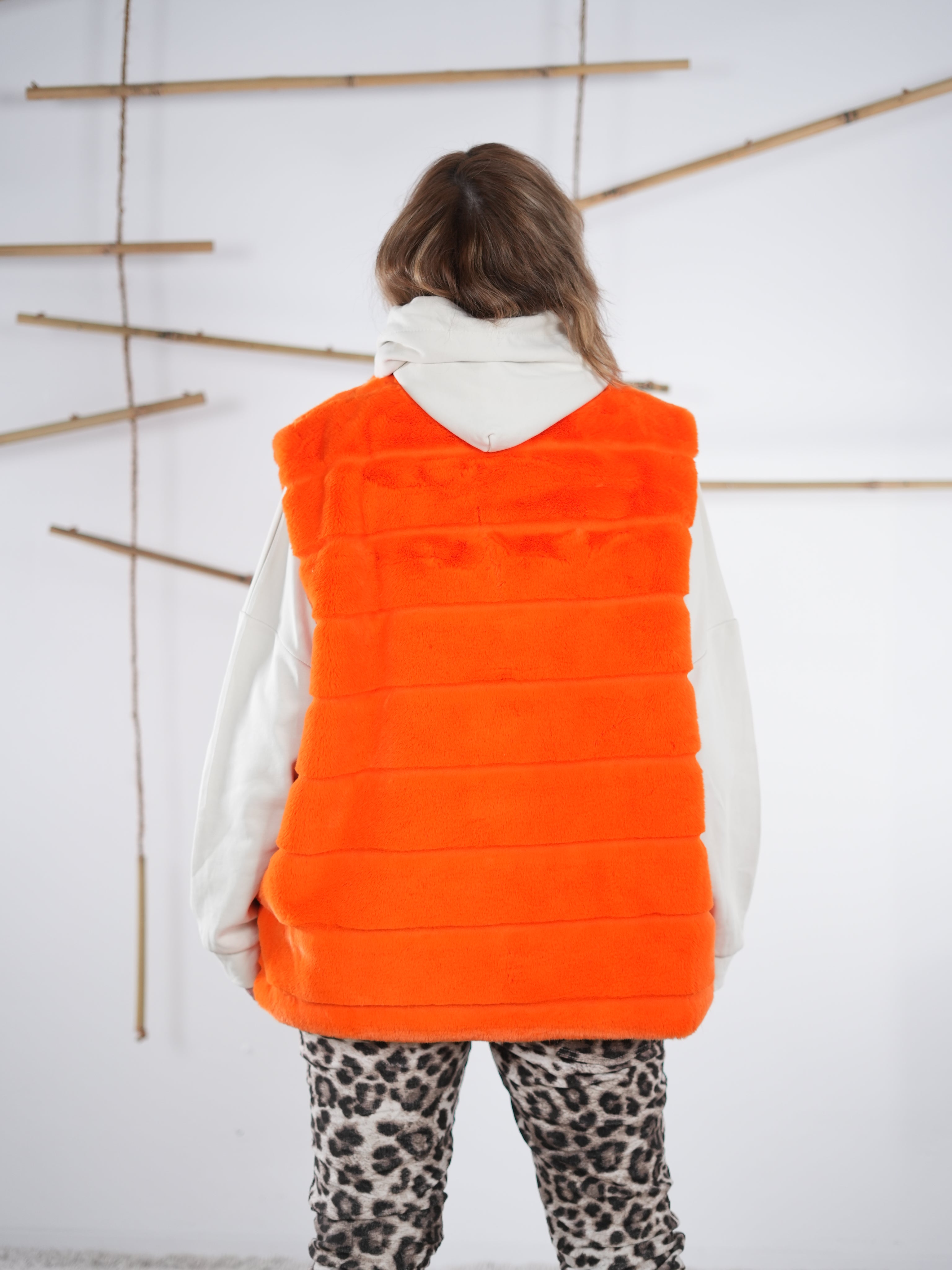 Rückansicht der orangefarbenen Flausch-Weste mit flauschiger Struktur und geradem Abschluss