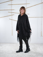 Seitliche Aufnahme der schwarzen Tunika mit Glitzer Elementen. Der weite Schnitt der Tunika fällt zudem auf .