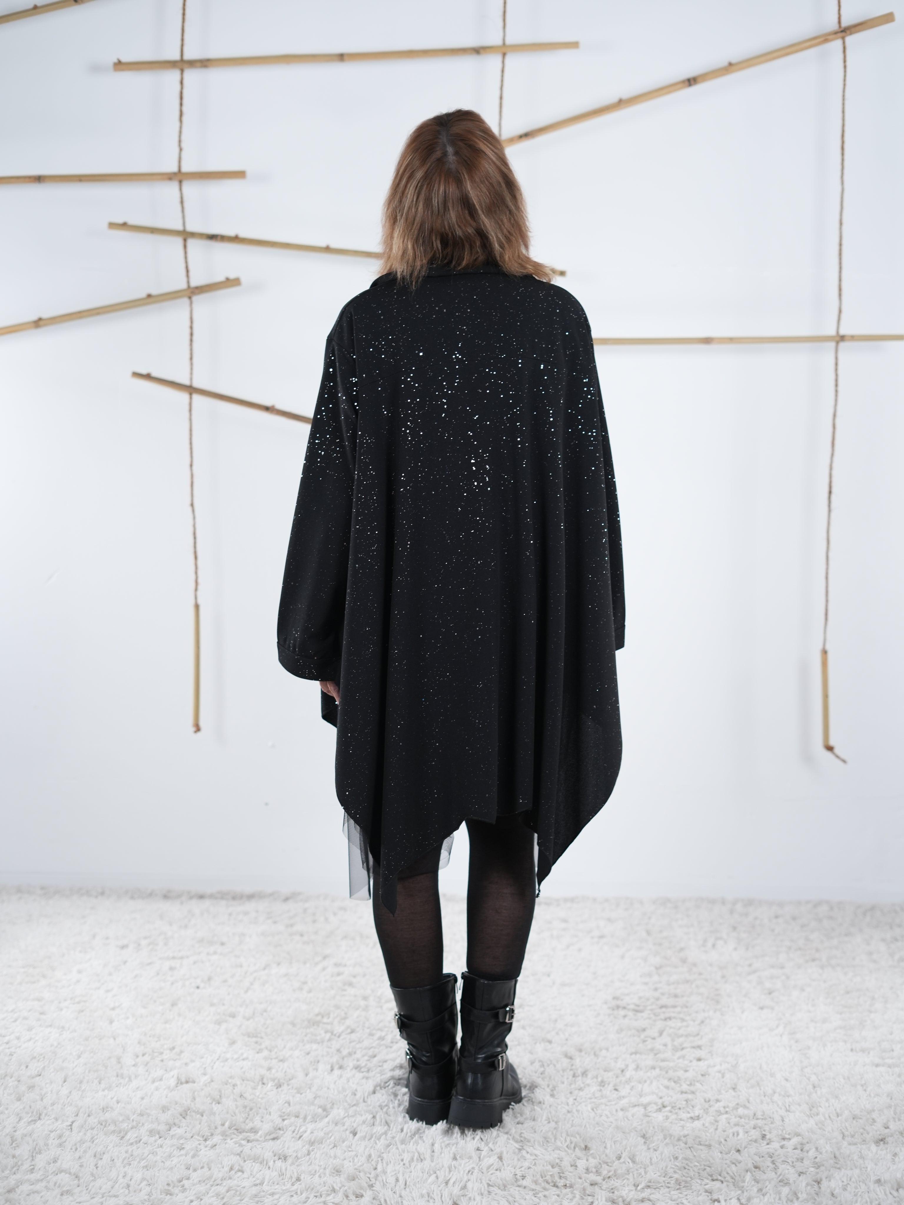 Rückenansicht der Tunika in schwarz. Die glitzernden Details funkeln. 