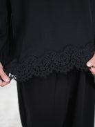 Detaillierte Ansicht eines lockeren, schwarzen Pullis mit Spitze verziert.