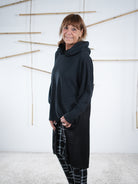 Schwarze Tunika mit Satin-Einsatz, seitlich schräg von hinten fotografiert, lang geschnitten.