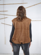 Rückansicht der camel­farbenen Velours-Weste in Lederoptik mit elastischem Abschluss.
