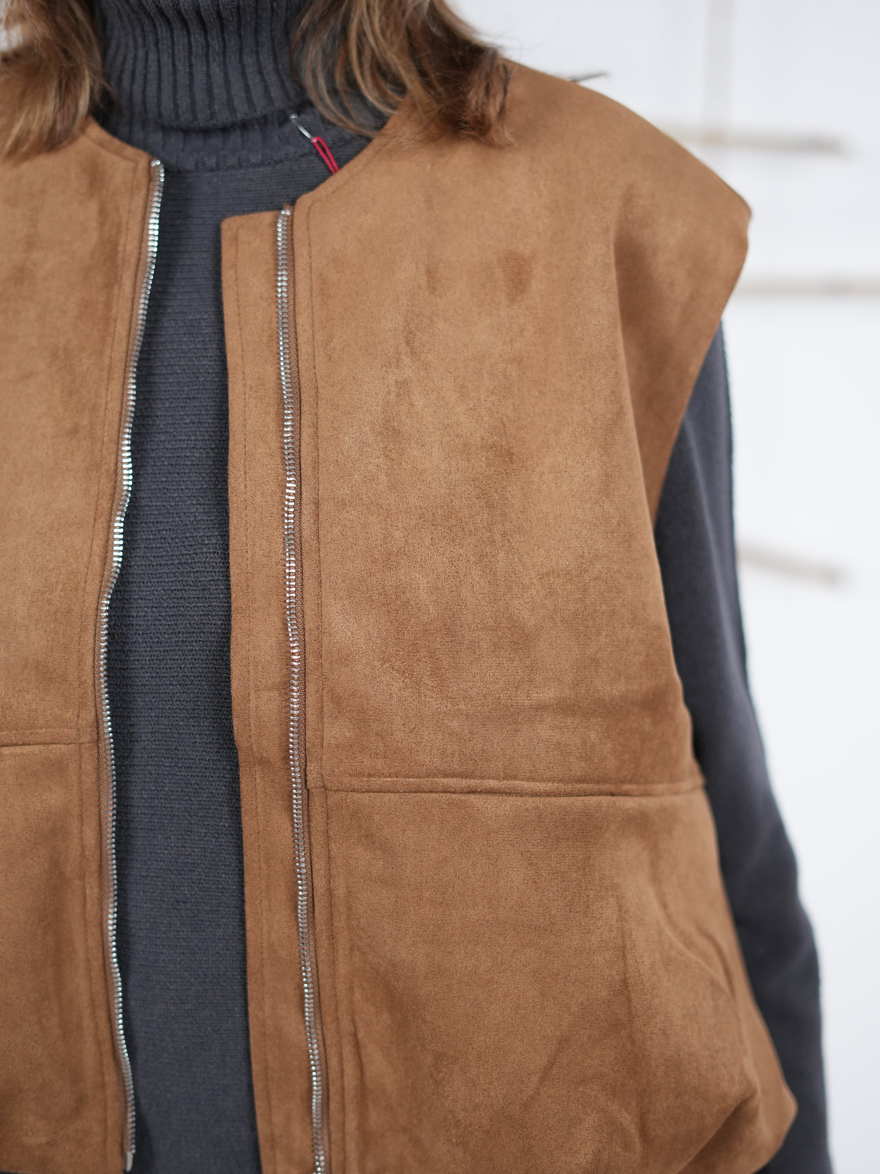 Detailansicht der Velours-Weste in Camel mit sichtbarer Lederoptik, Reißverschluss und rundem Halsausschnitt