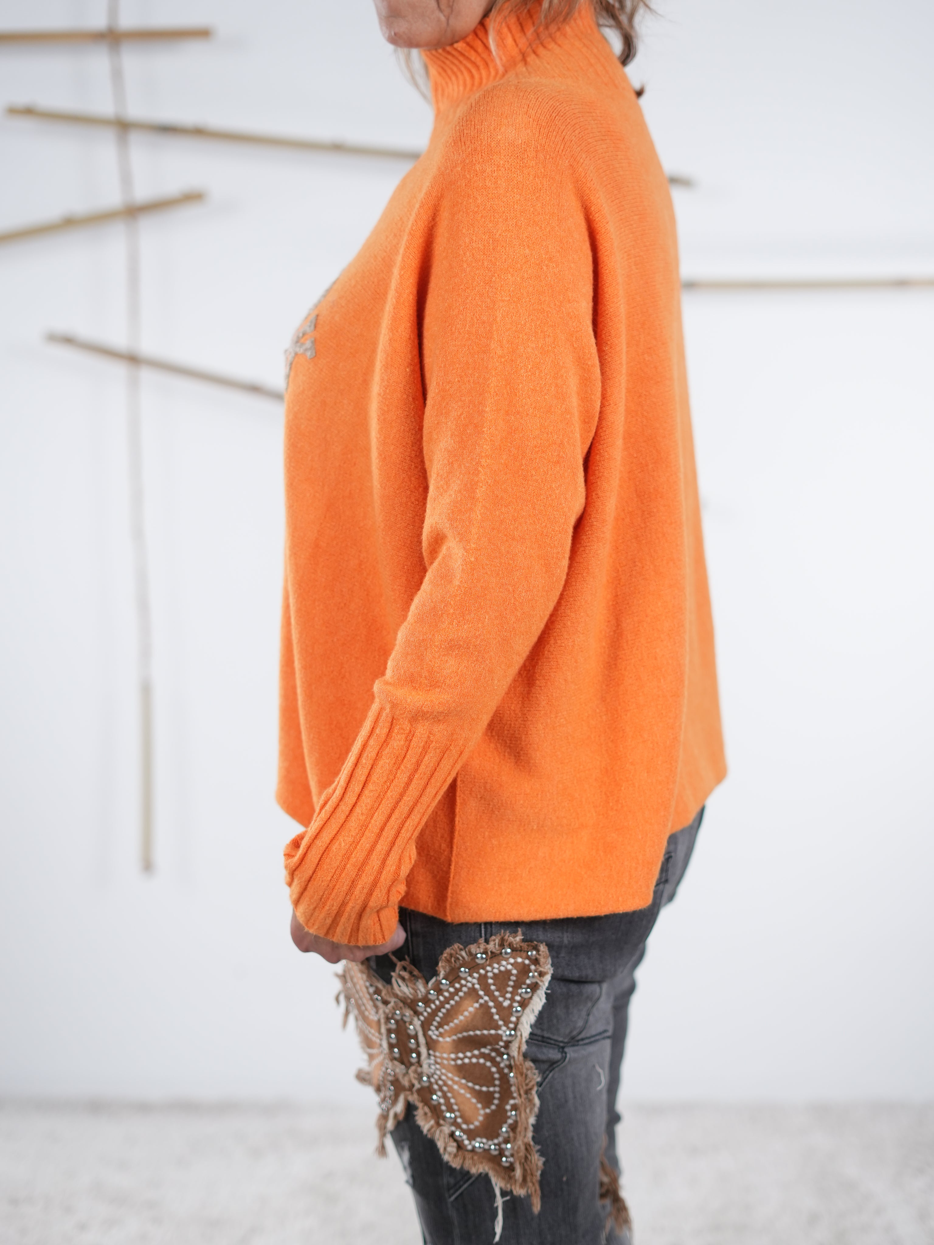 Seitliche Ansicht eines orangefarbenen Damen-Pullovers mit Stehkragen und „New York“-Schriftzug.