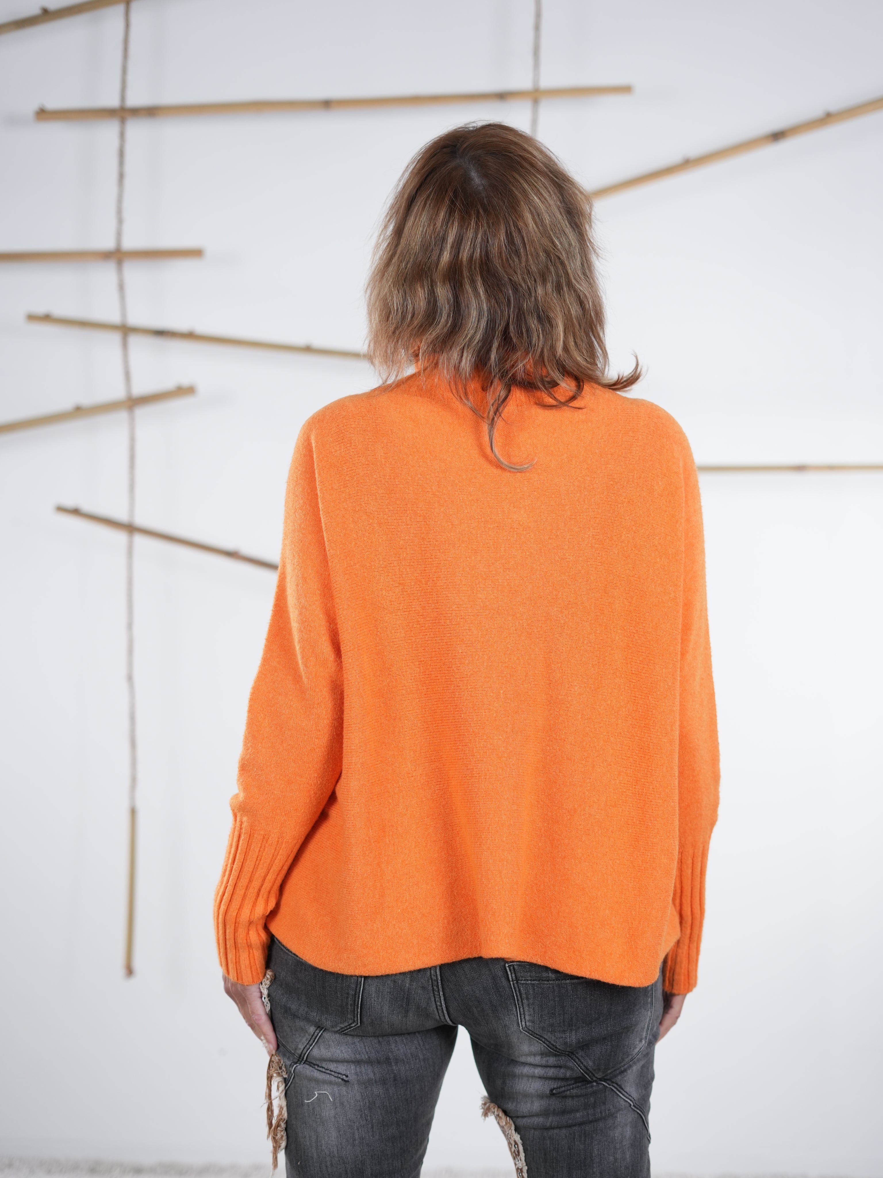 Rückenansicht eines orangefarbenen Oversize-Pullovers mit Rippärmeln.