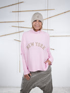 Rosa Damen-Pullover mit beigem „New York“-Schriftzug in lockerem Schnitt, Frontansicht.