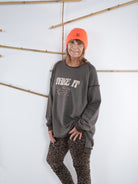 Seitliche Ansicht eines schokobraunen Vokuhila-Sweatshirts mit ausgefransten Nähten, kombiniert mit Leo-Leggings